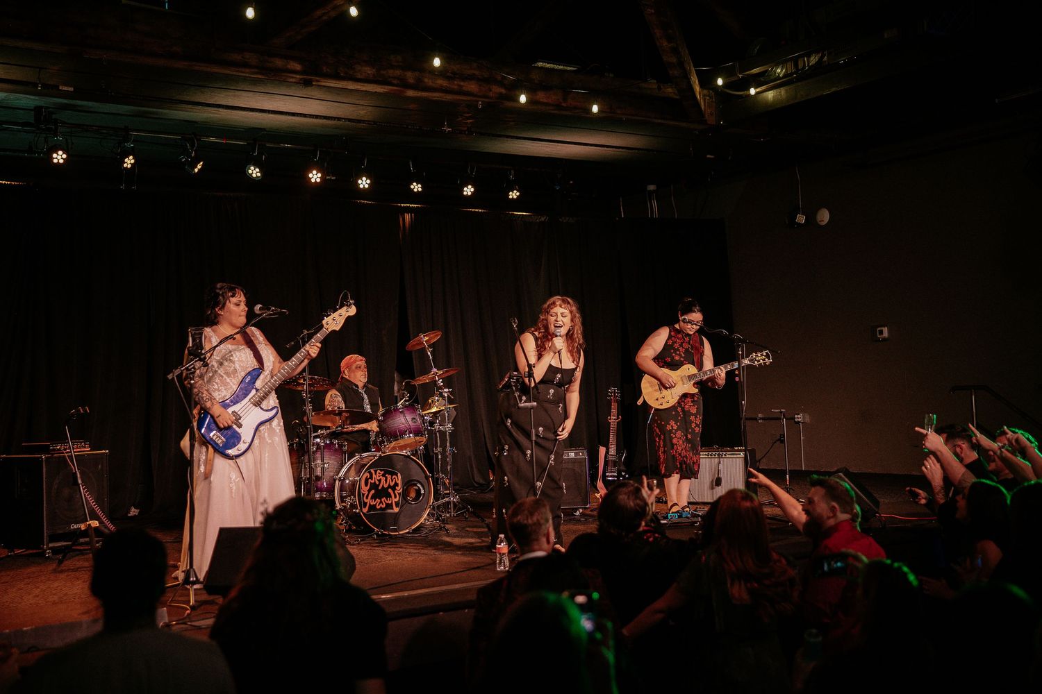 A live band performs on stage at a vibrant wedding reception with an enthusiastic crowd.