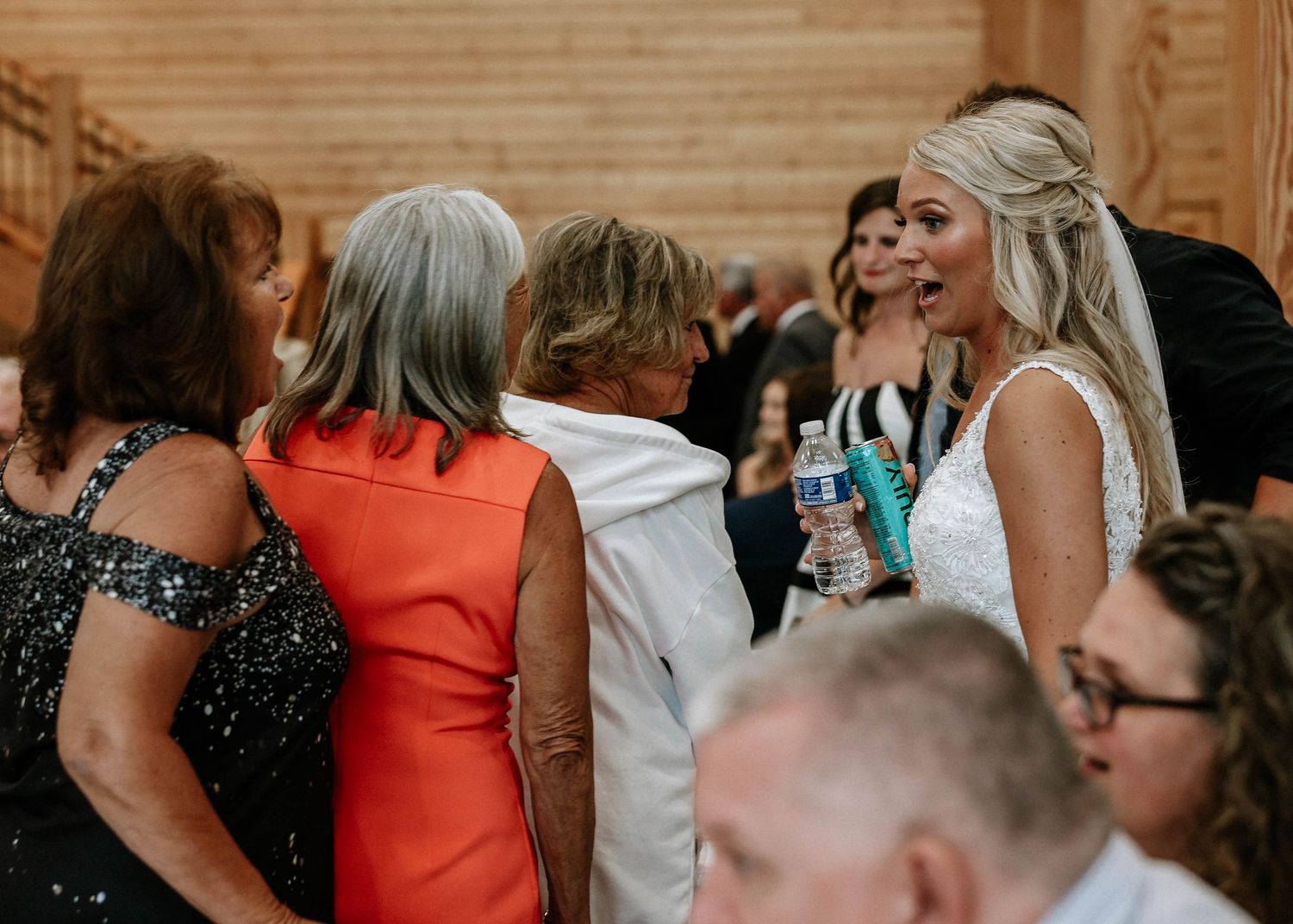 Bride in white wedding gown laughing with guests during wedding reception celebration.