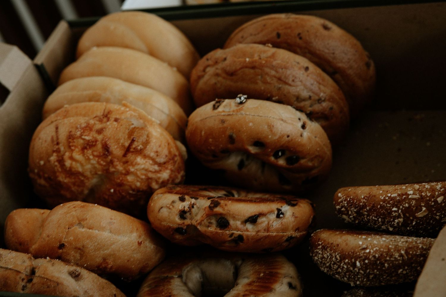 An assortment of fresh bagels including plain, sesame, and chocolate chip varieties arranged in a box at Urban Artifact in Cincinnati, Ohio