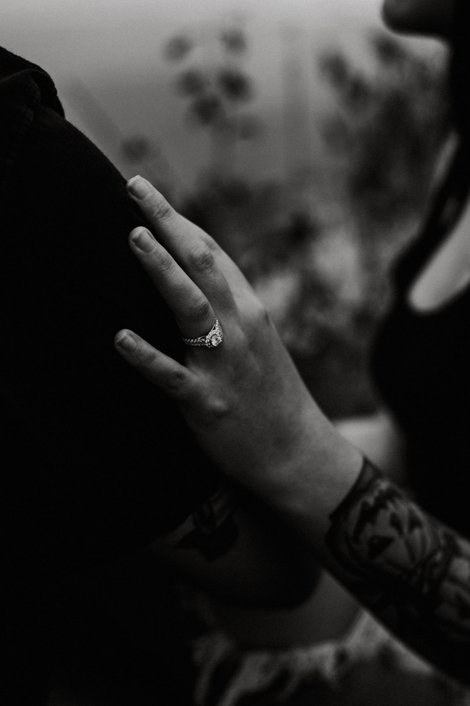 Black and white close-up of a hand with an elegant ring resting on a shoulder, tattoo visible on wrist at Oakes Quarry Park in Dayton, Ohio