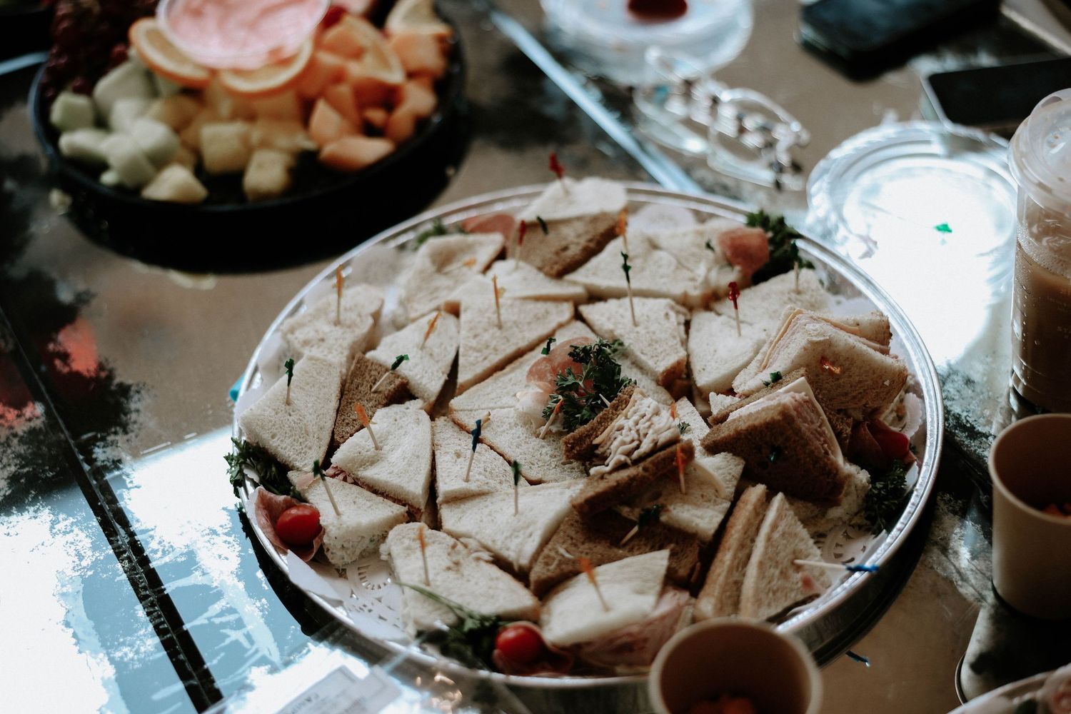 Elegant wedding reception finger sandwiches arranged on a round platter with cherry tomato garnishes.