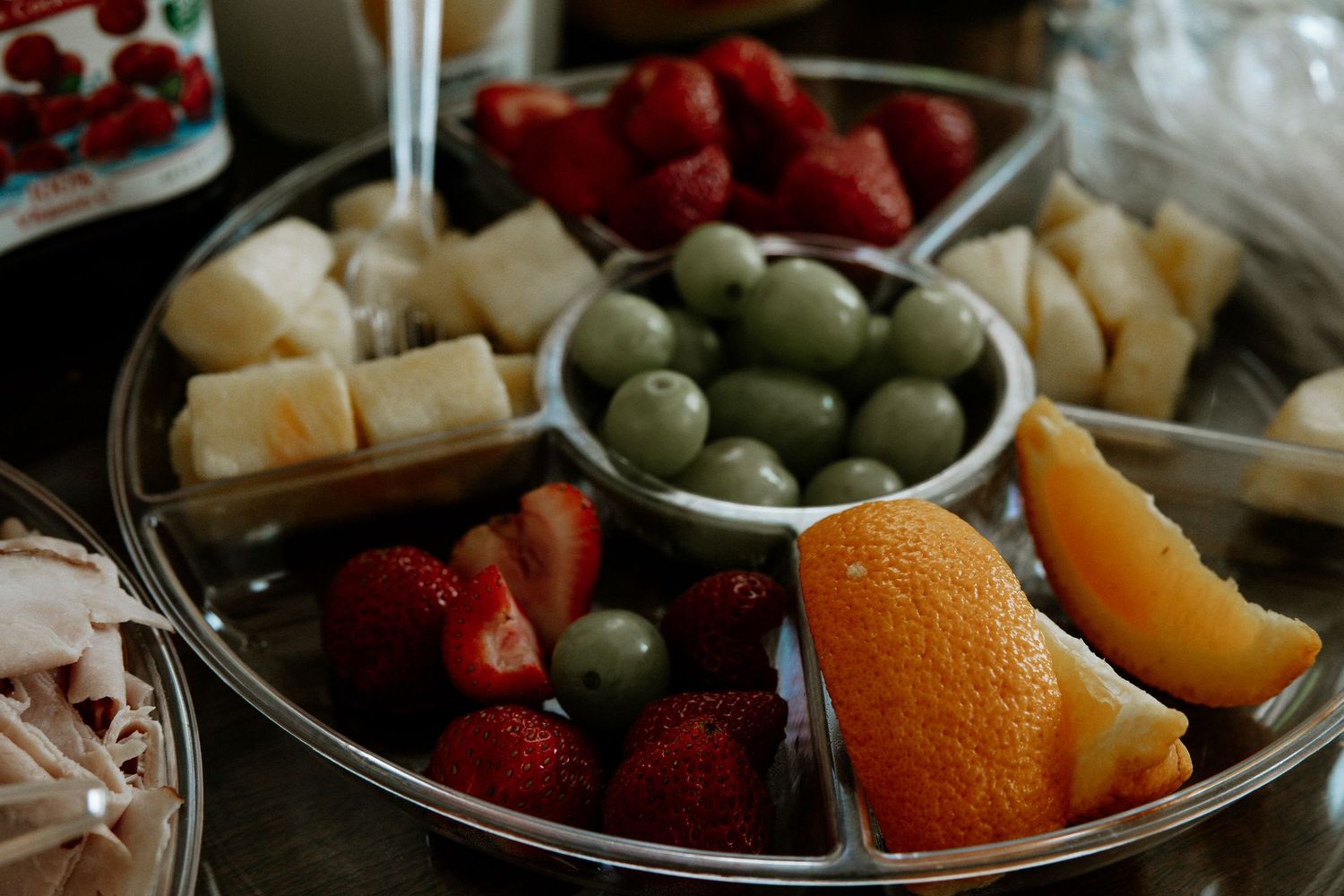 A silver divided tray filled with fresh strawberries, orange slices, green olives, and cheese cubes at Urban Artifact in Cincinnati, Ohio
