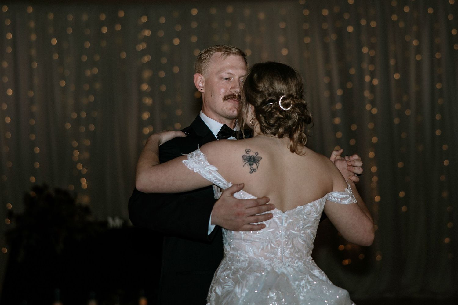 Bride and groom share intimate first dance, bride showing floral back tattoo in lace gown at Urban Artifact in Cincinnati, Ohio