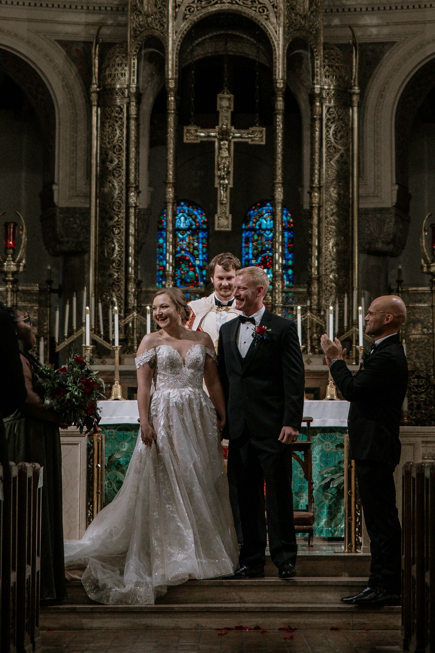 Newlyweds smile joyfully at the altar with officiant in a beautifully decorated historic church in Cincinnati, Ohio