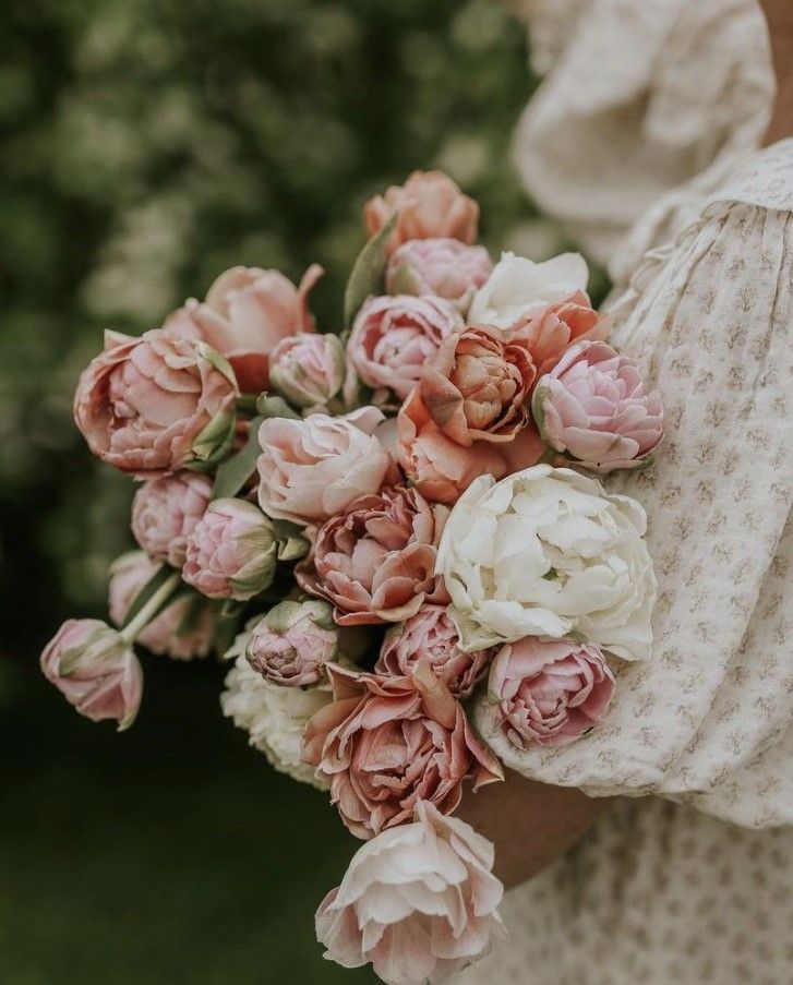 Person holding a lush bouquet of pink and white peonies and roses outdoors in Cincinnati, Ohio.