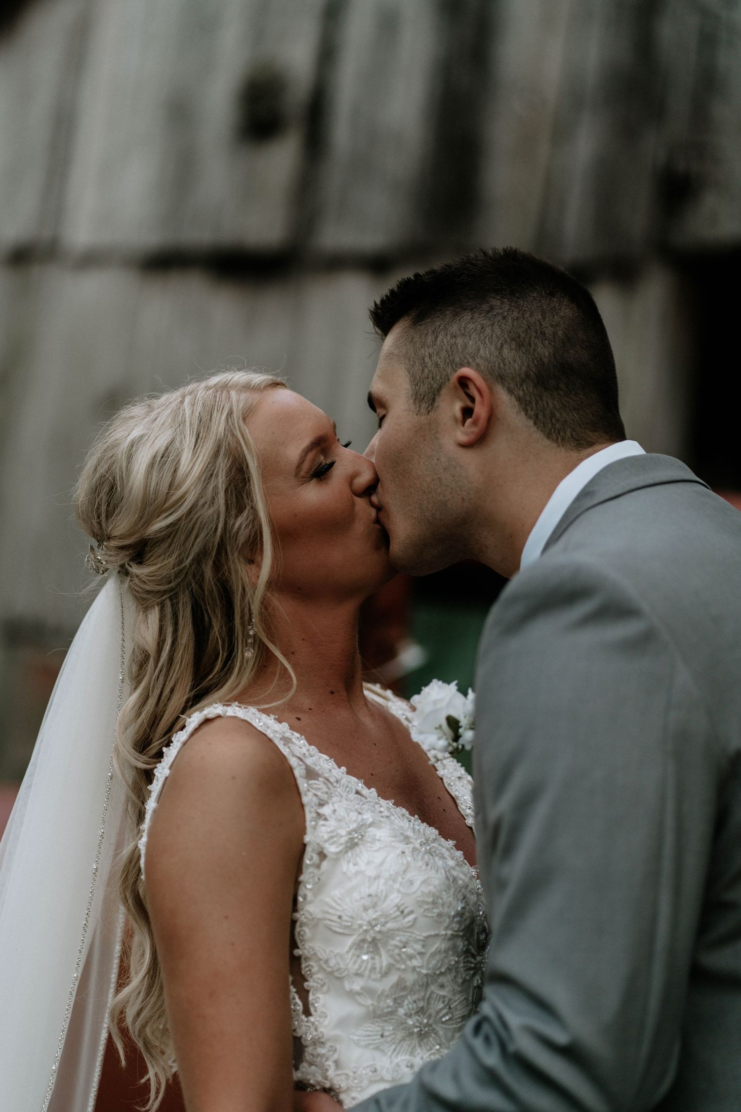 Bride and groom share a romantic first kiss at their wedding ceremony outdoors.