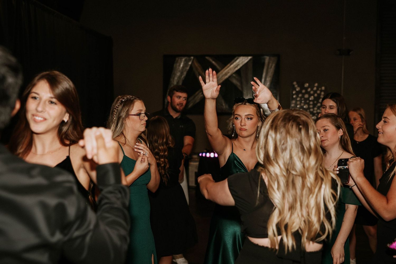 Guests in elegant green dresses dancing and celebrating at a formal event or wedding reception.
