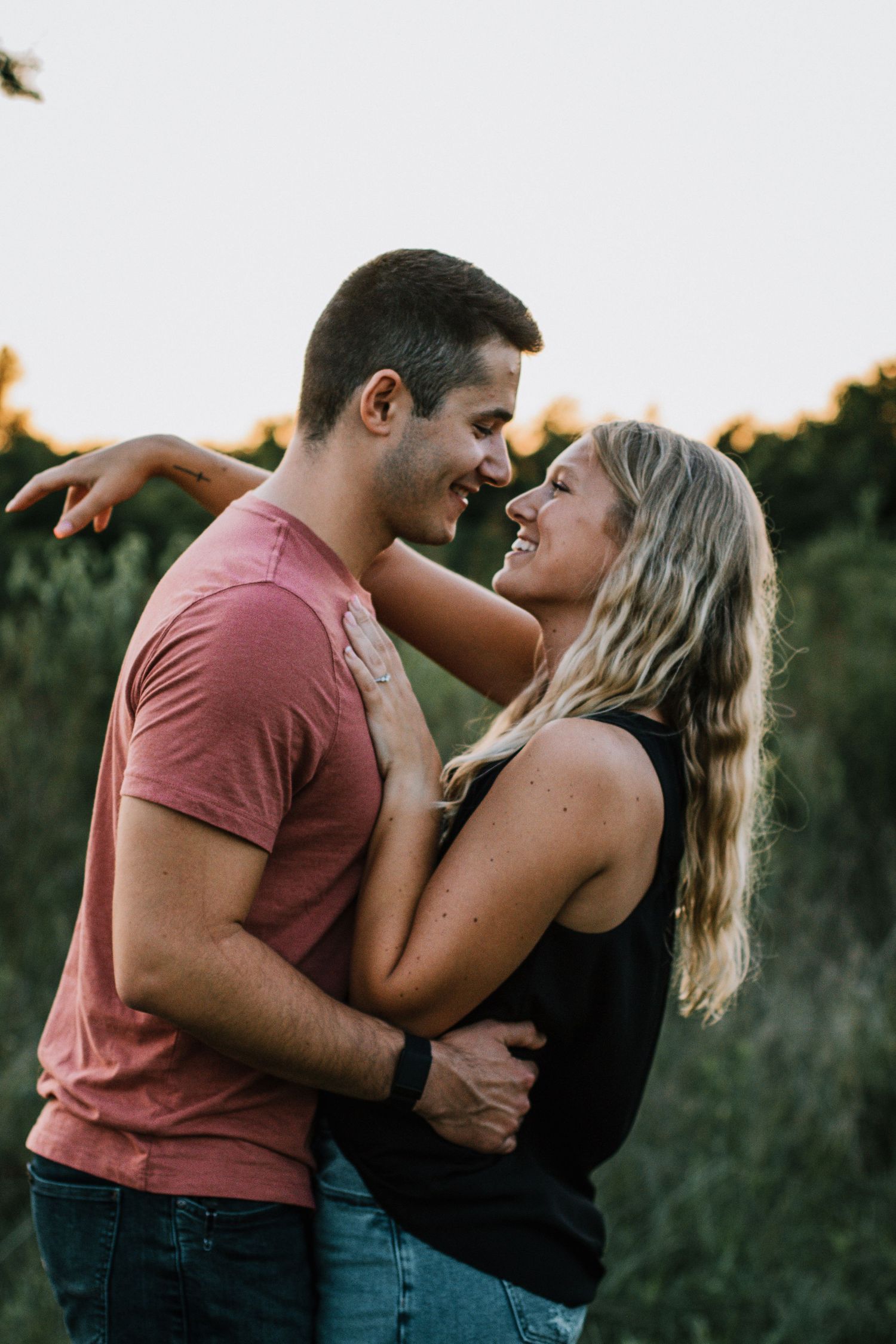 Happy couple embracing and smiling at each other in a golden hour outdoor field setting in Cincinnati, Ohio