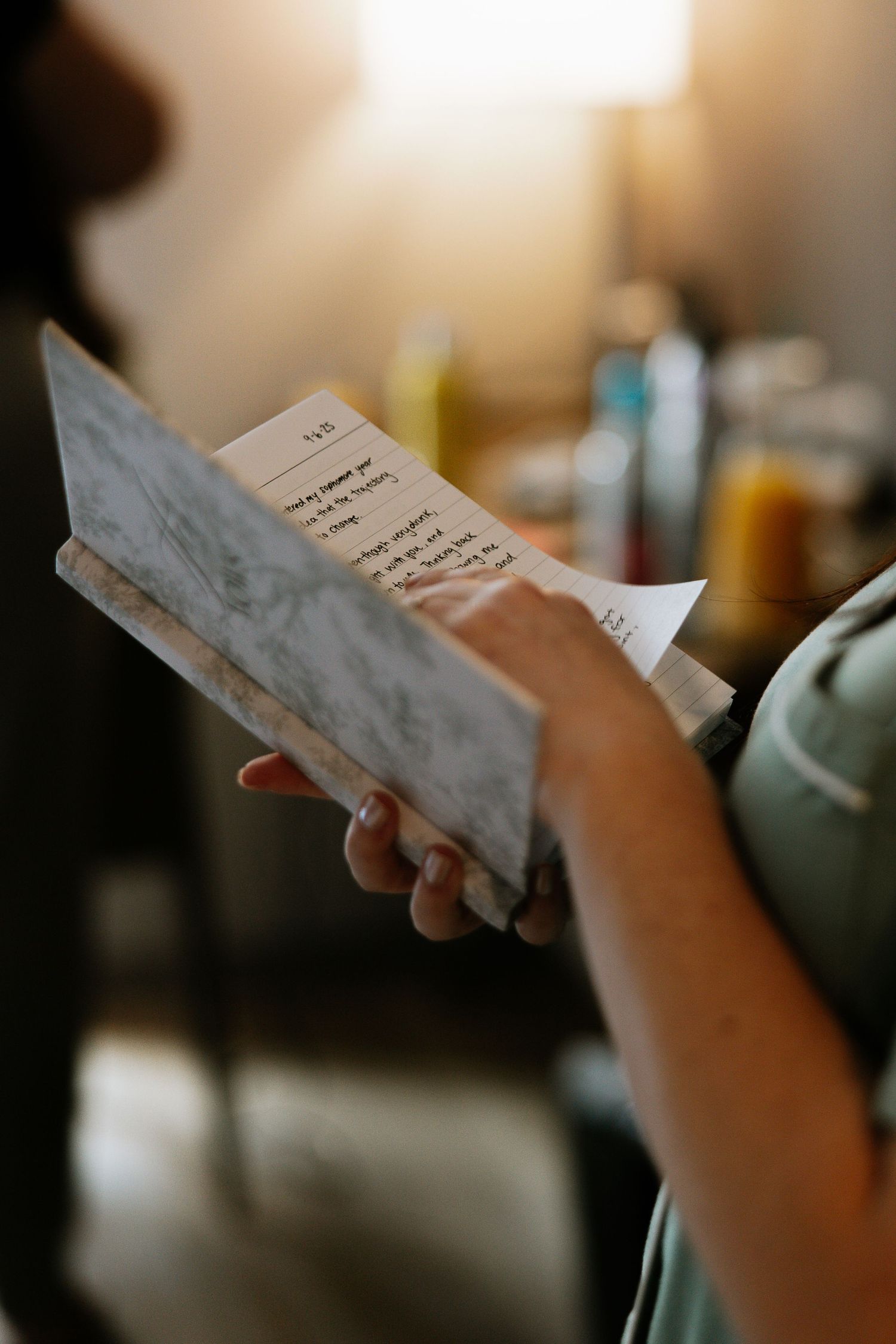 Close-up of hands holding an open card with handwritten notes in a warmly lit room.