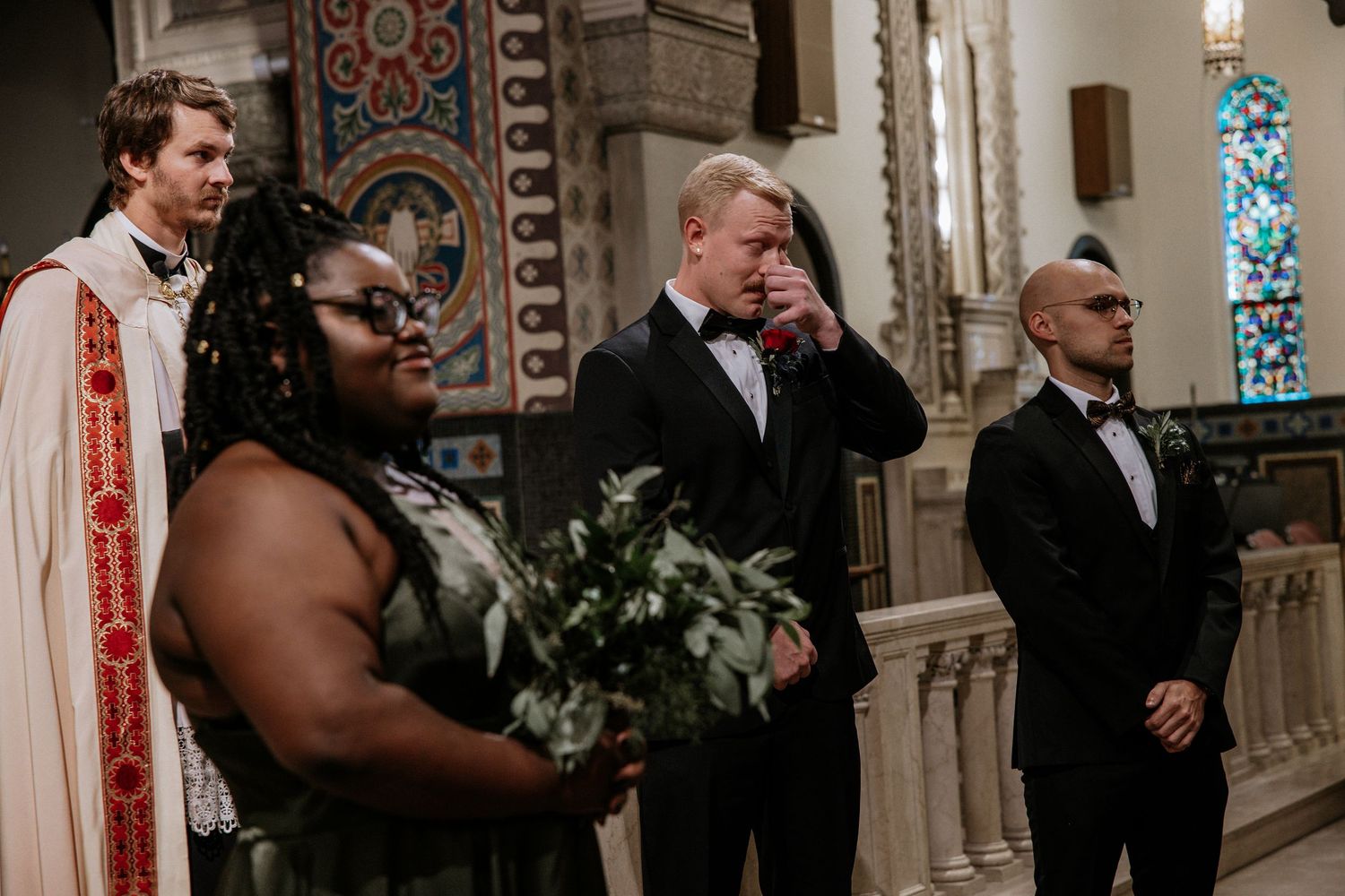 Emotional groom wipes tears while standing at church altar with wedding party during ceremony in Cincinnati, Ohio