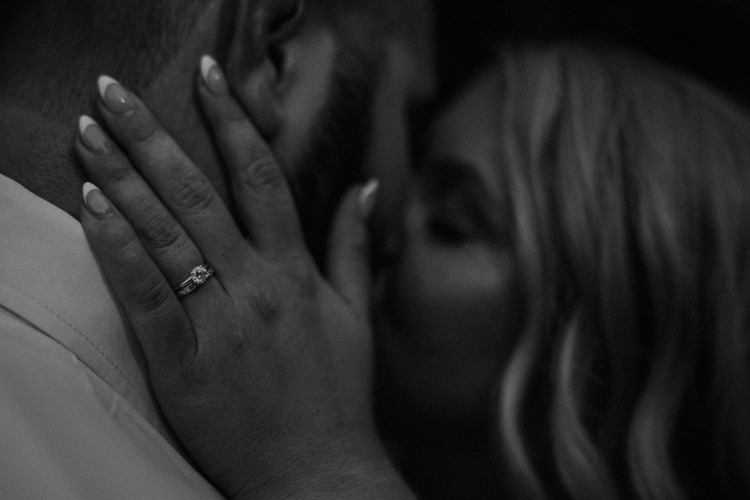 Black and white close-up of bride's hand with engagement ring resting on groom's chest while kissing at The Brightside in Dayton, Ohio