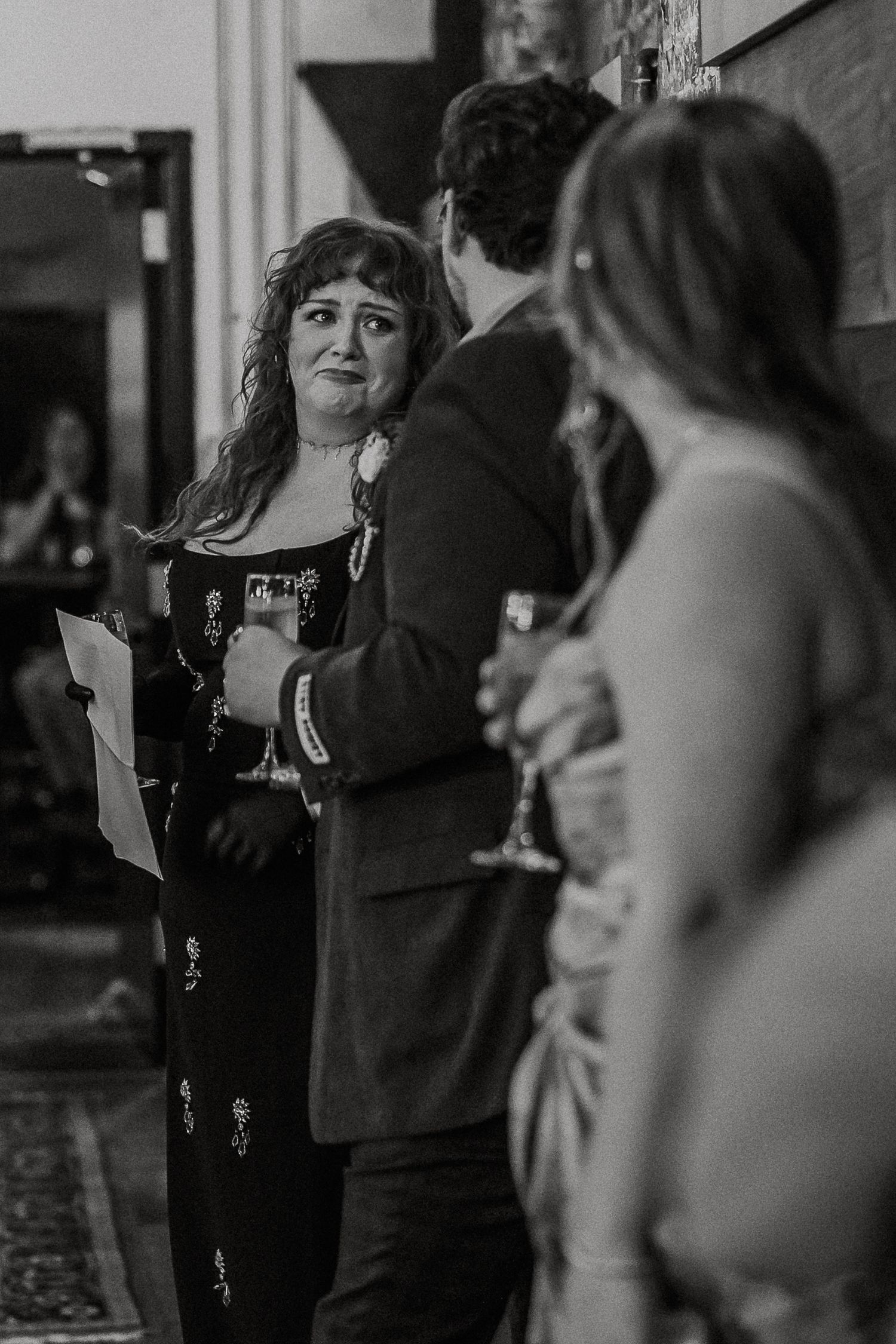 Black and white photo of emotional woman giving heartfelt speech at wedding reception.