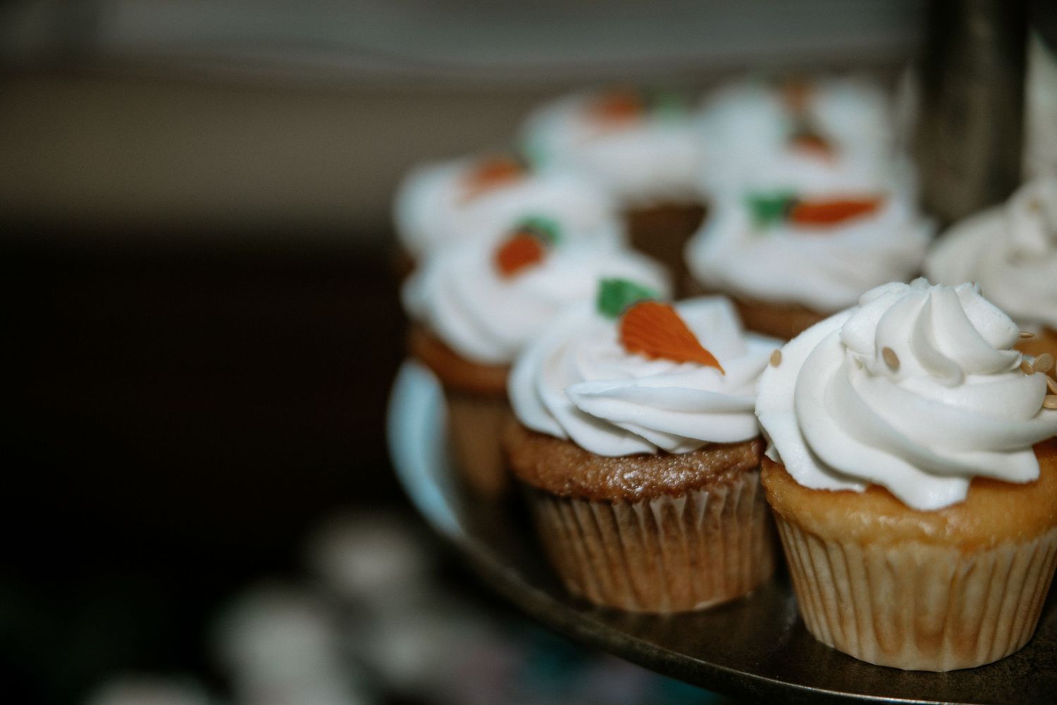Carrot cupcakes topped with swirled white frosting and decorative carrot accents on a tiered stand at Urban Artifact in Cincinnati, Ohio