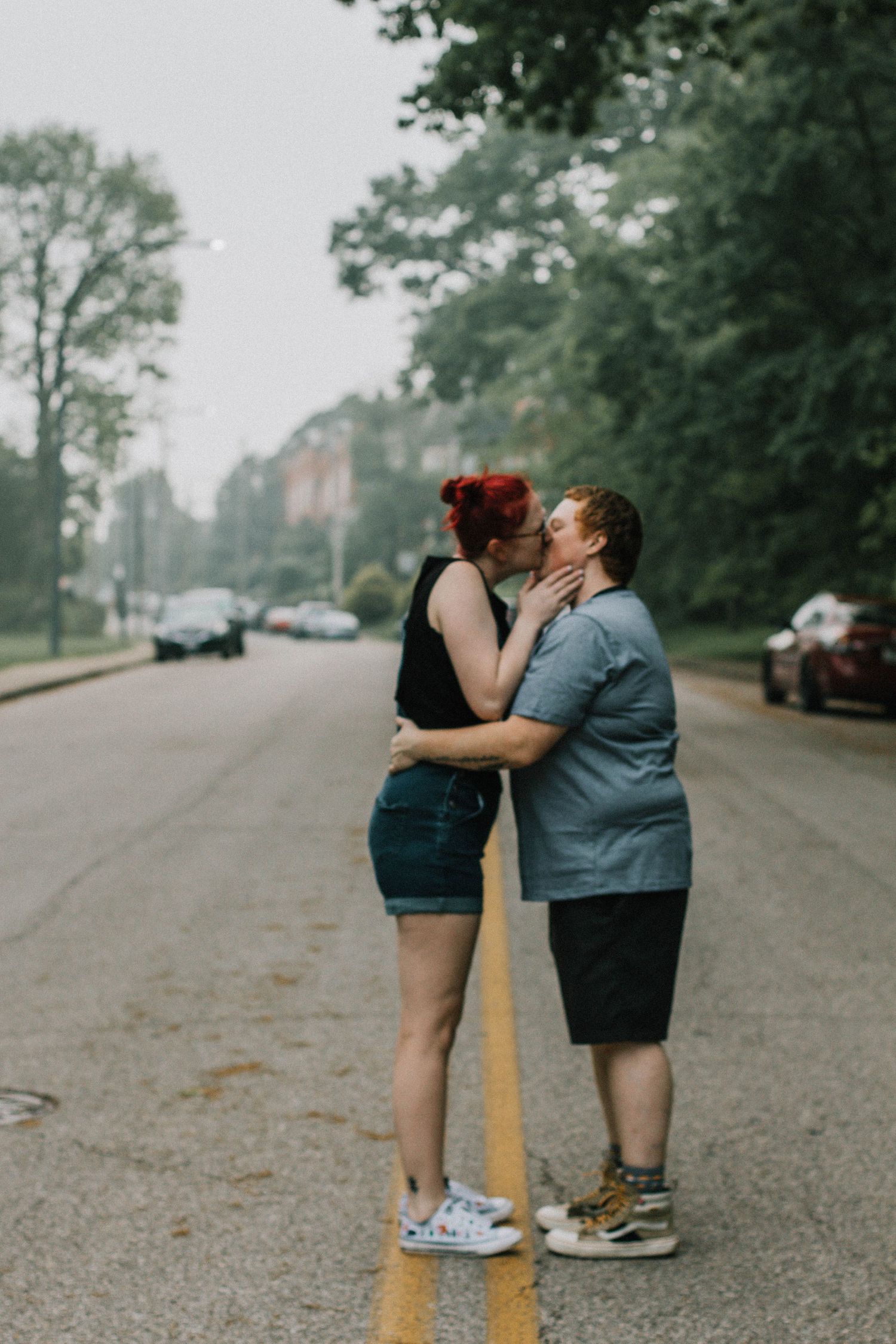 LGBT Couple kissing on yellow center line of tree-lined street at Eden Park in Cincinnati, Ohio