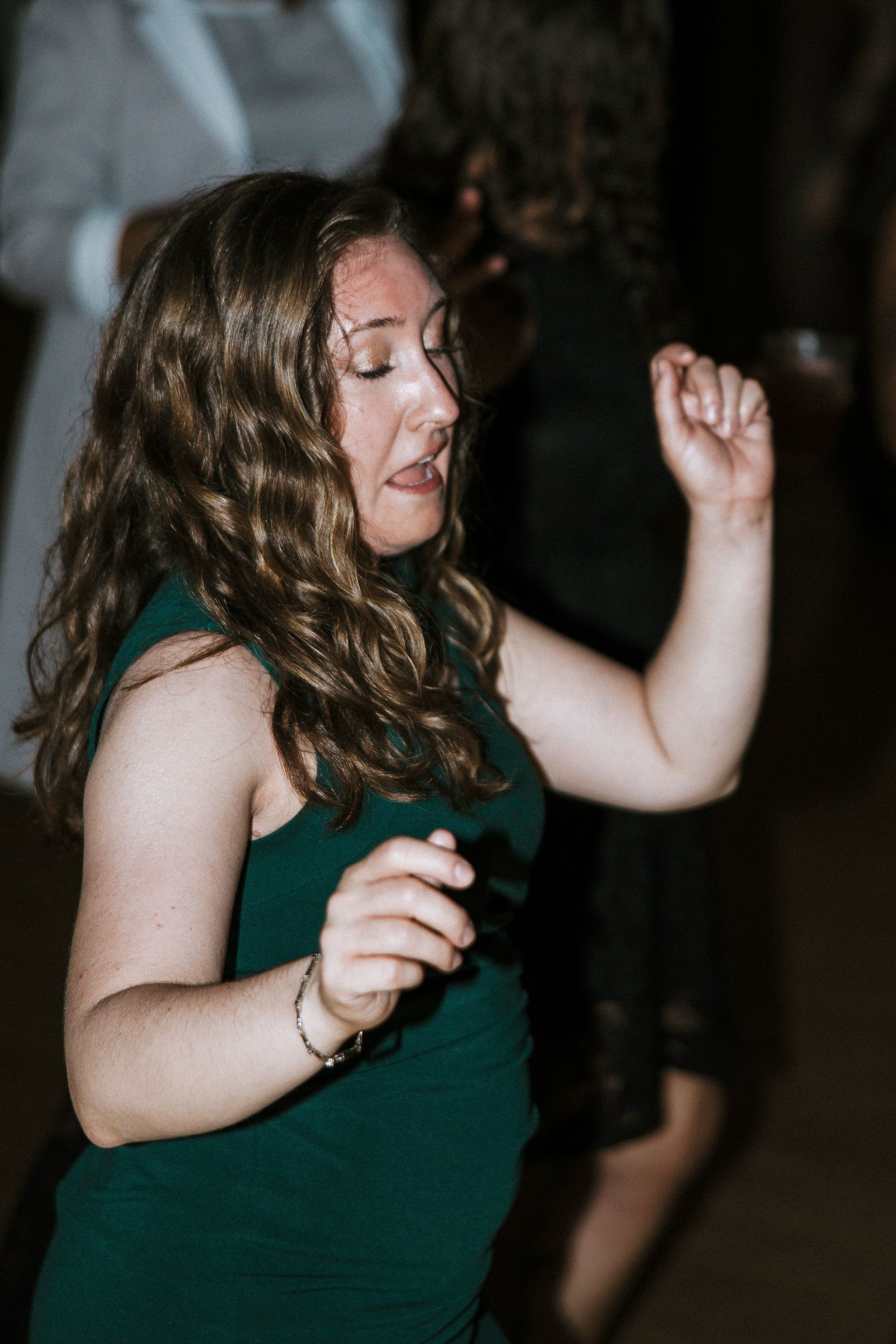 Woman with curly hair dancing with eyes closed at wedding reception in Cincinnati, Ohio