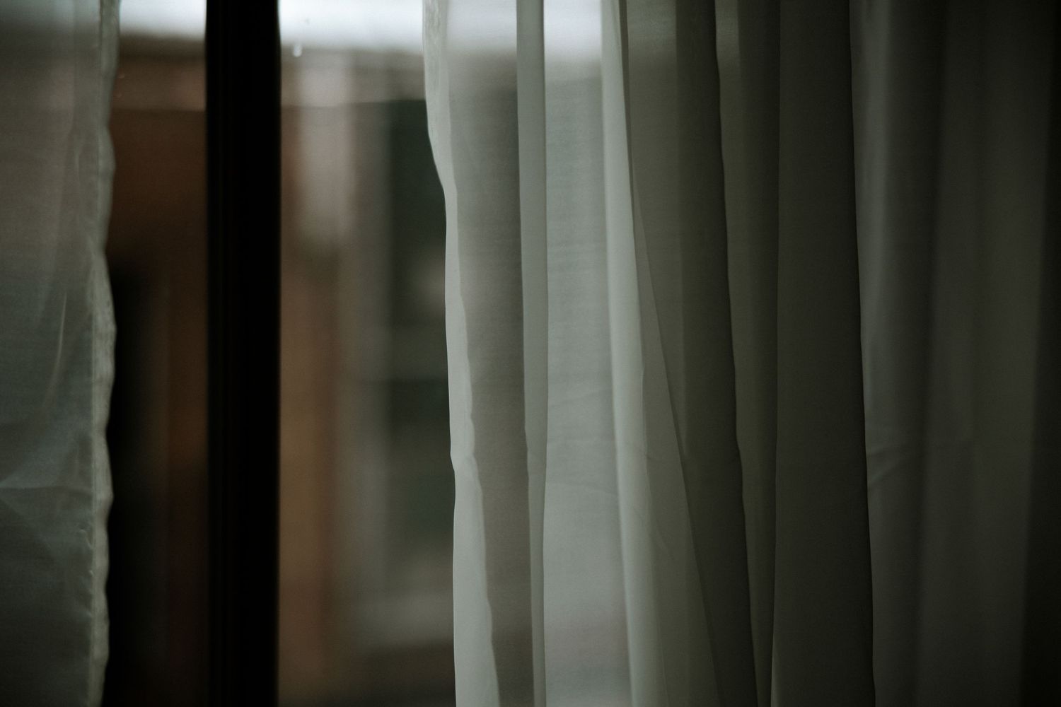 Soft white sheer curtains hanging by a window in soft natural light at Urban Artifact in Cincinnati, Ohio