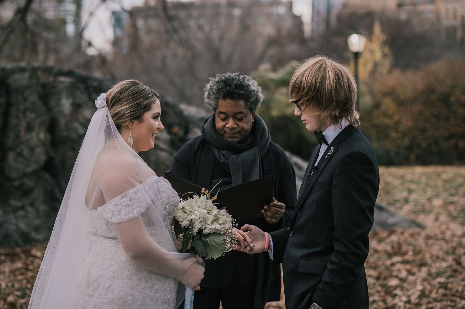 Bride and groom exchanging vows with officiant in Central Park during intimate outdoor wedding ceremony.