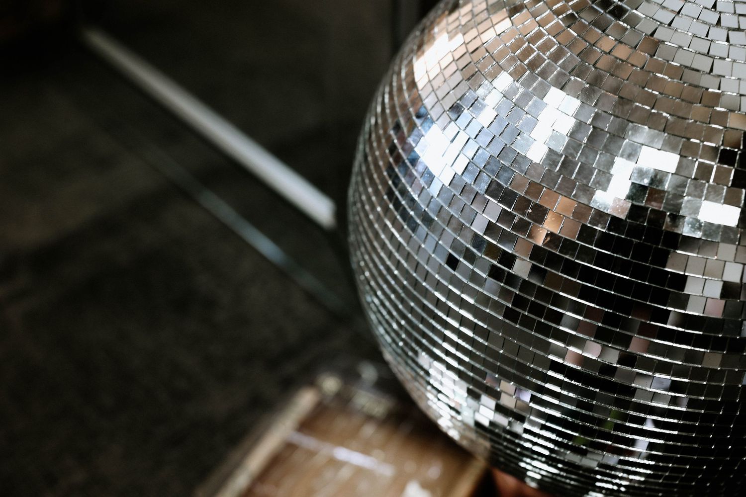 A shiny silver disco ball reflecting light on a dark background.