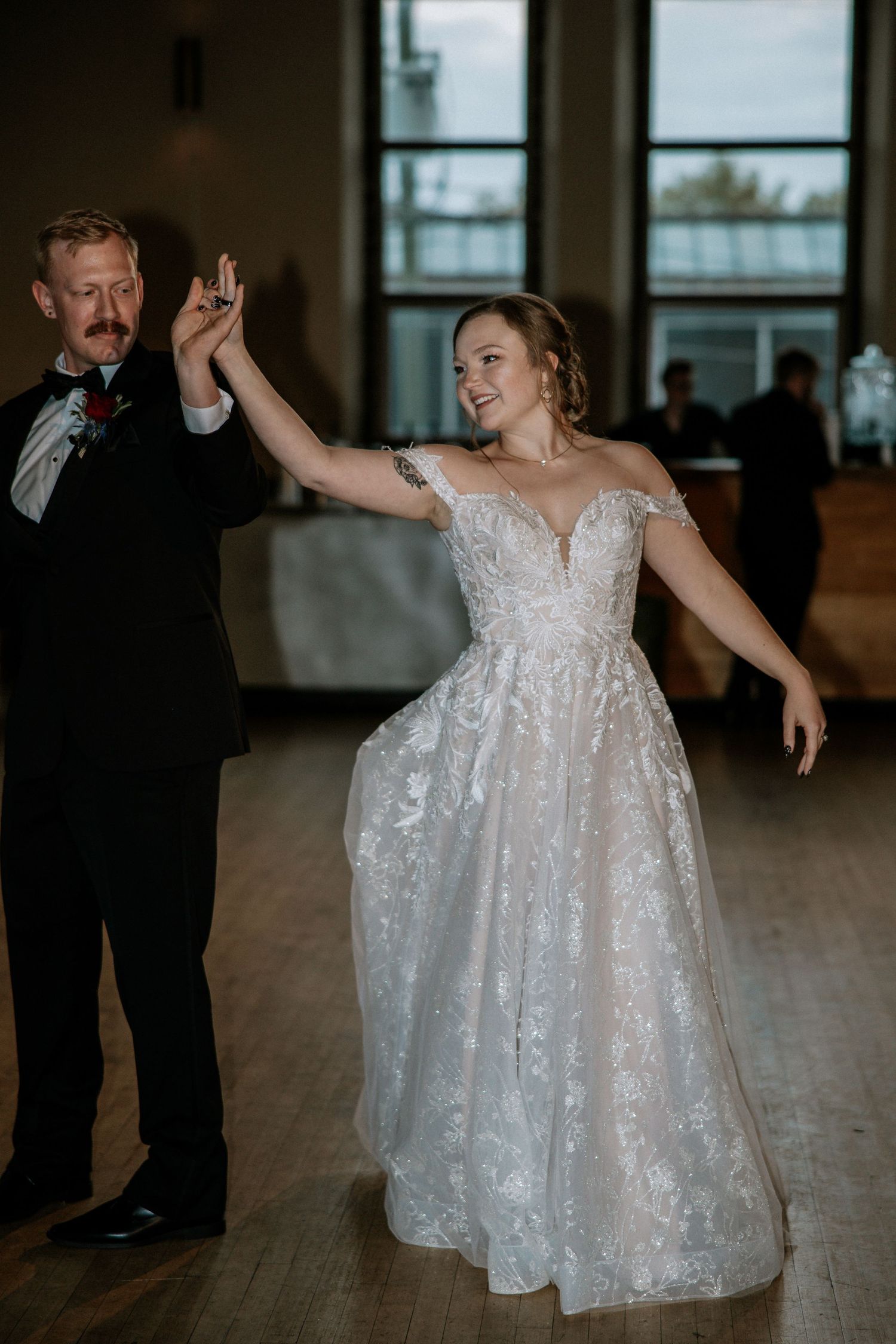 Bride in lace ballgown spins joyfully with groom during wedding reception first dance at Urban Artifact in Cincinnati, Ohio