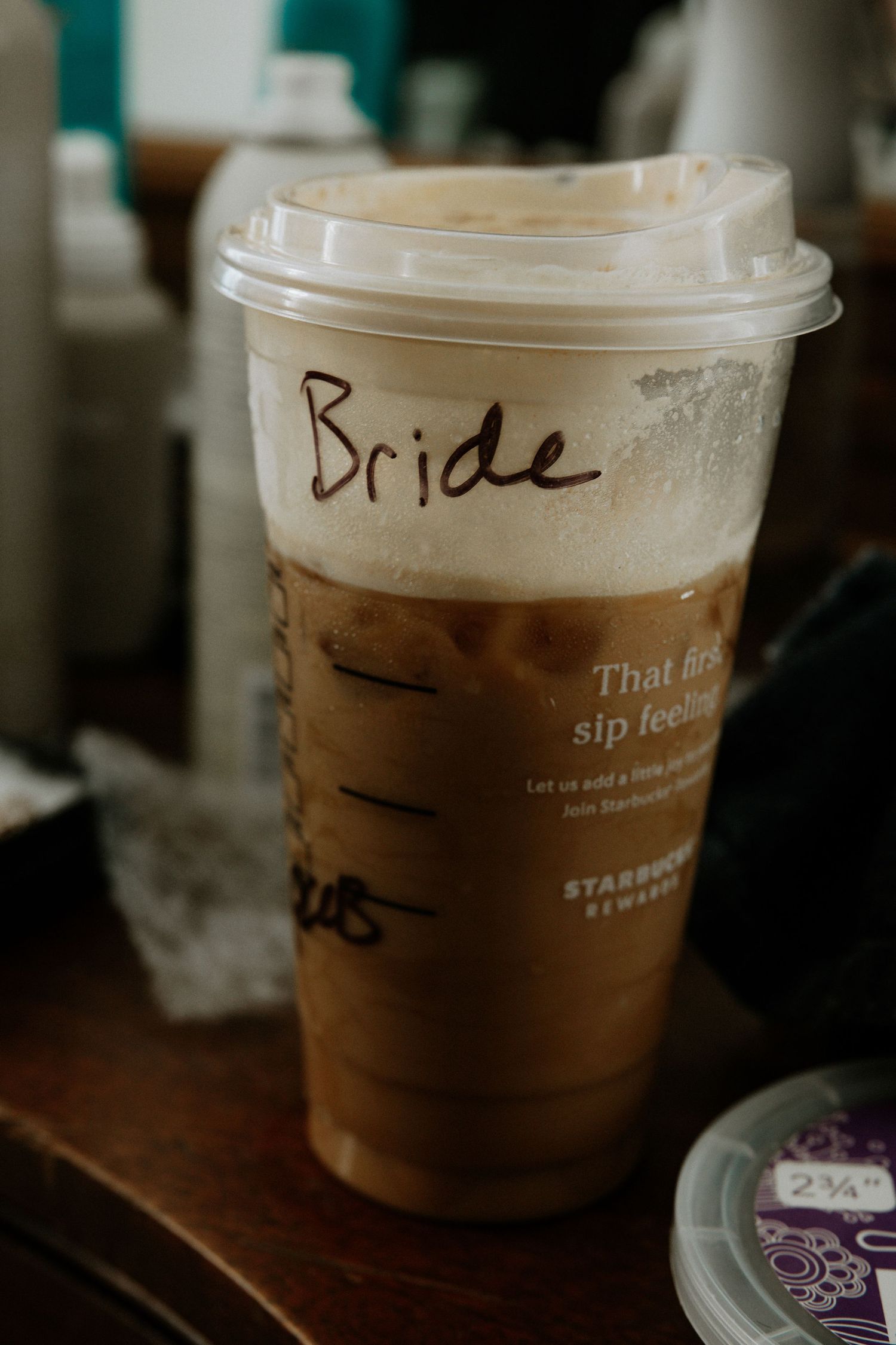 Starbucks iced coffee cup labeled Bride sitting on a wooden table at a wedding getting ready at Urban Artifact in Cincinnati, Ohio
