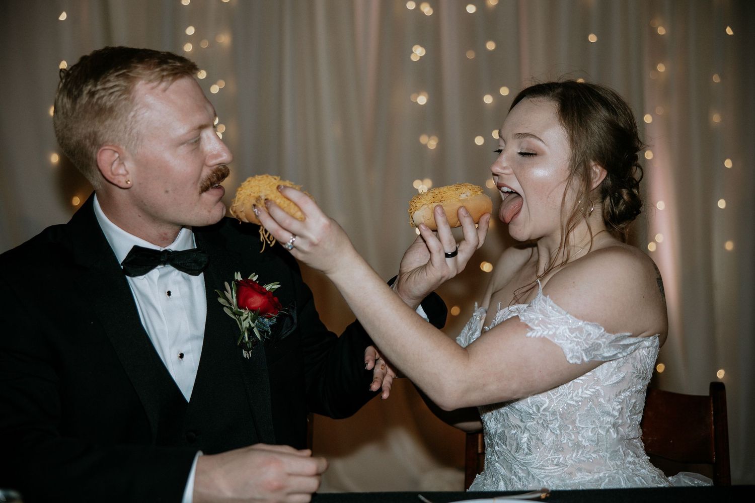 Bride and groom playfully feeding each other tacos at their wedding reception dinner table at Urban Artifact in Cincinnati, Ohio