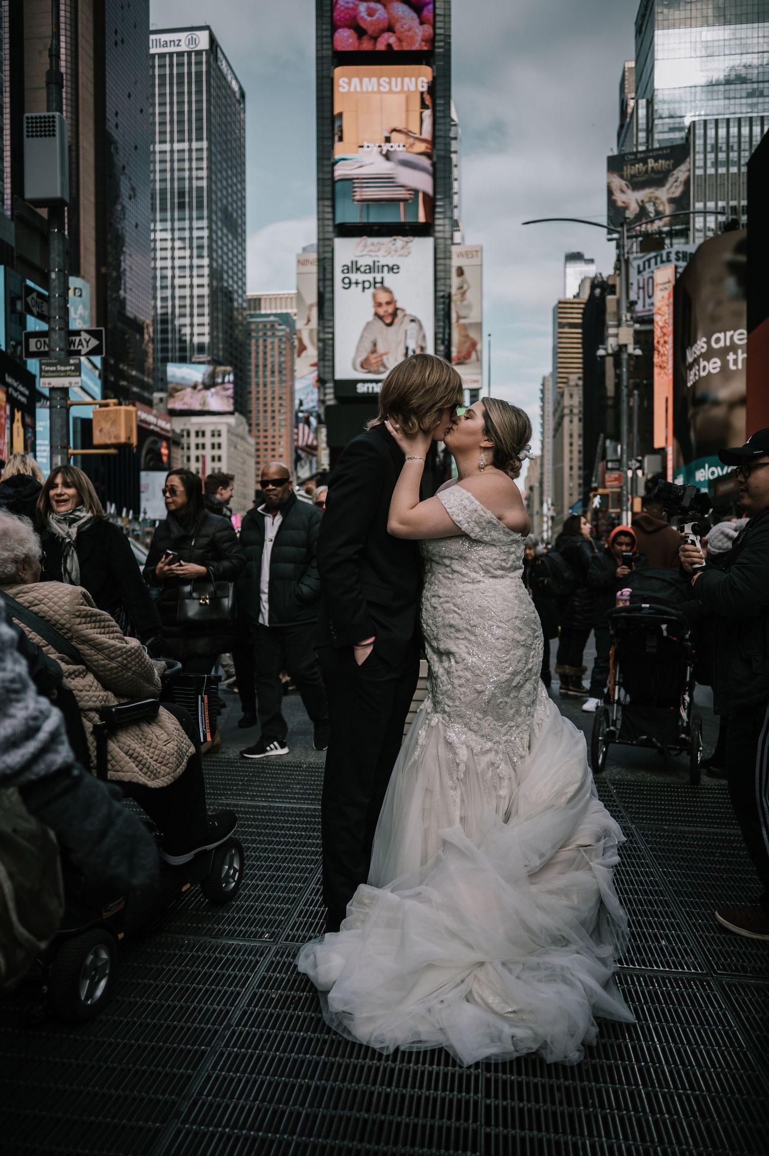 Bride and groom sharing a kiss in Times Square NYC, surrounded by iconic billboards and city crowds.