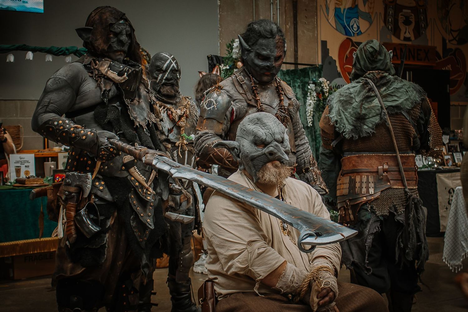 Group of people in orc costumes with weapons at a fantasy convention cosplay event.