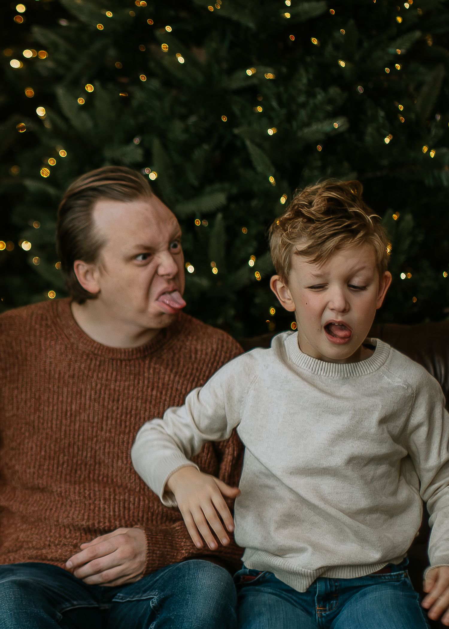 Father and son making silly faces together in front of a Christmas tree at Mill Street Studios in Cincinnati, Ohio.