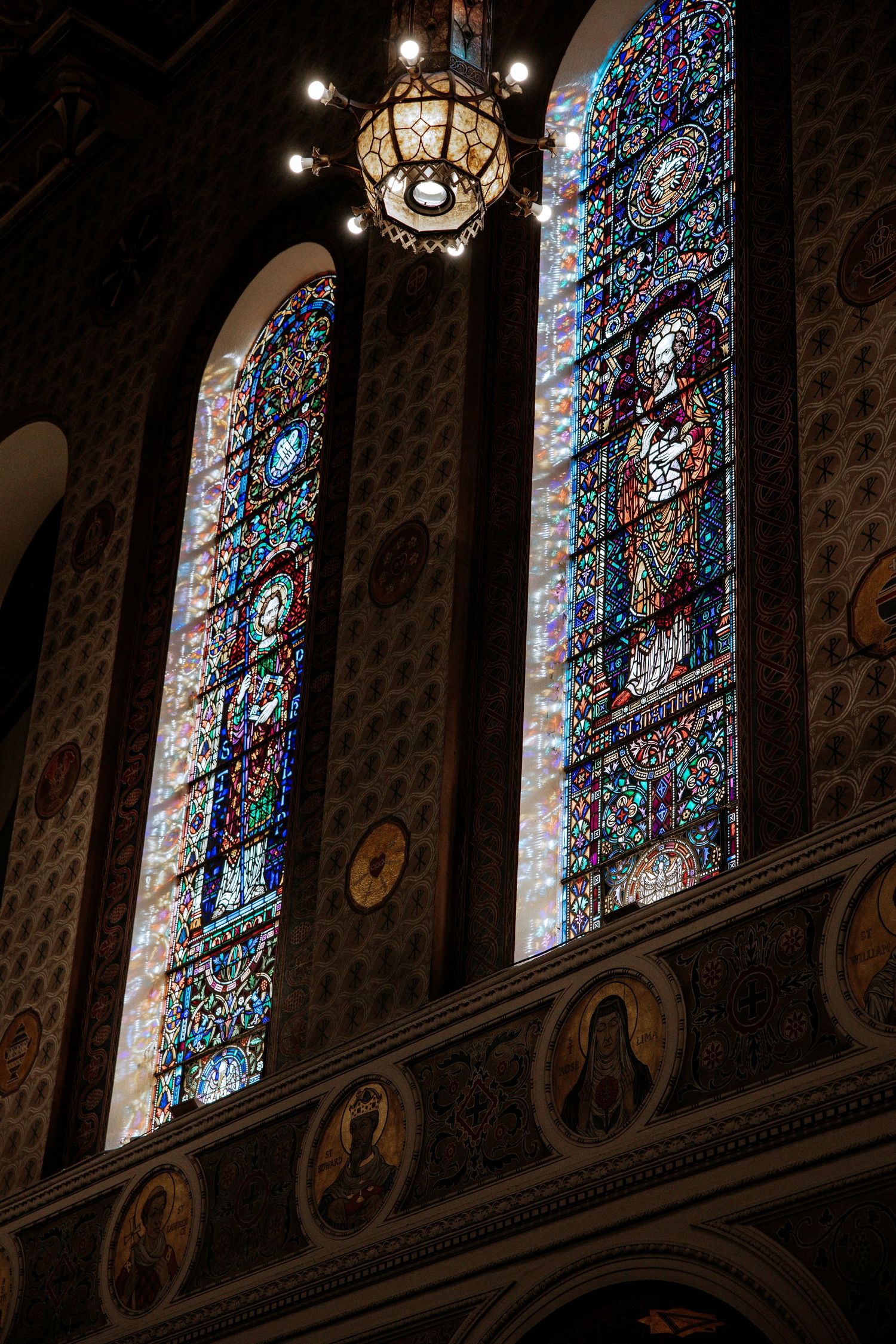Ornate church interior featuring tall colorful stained glass windows and decorative mosaic medallions on walls in Cincinnati, Ohio