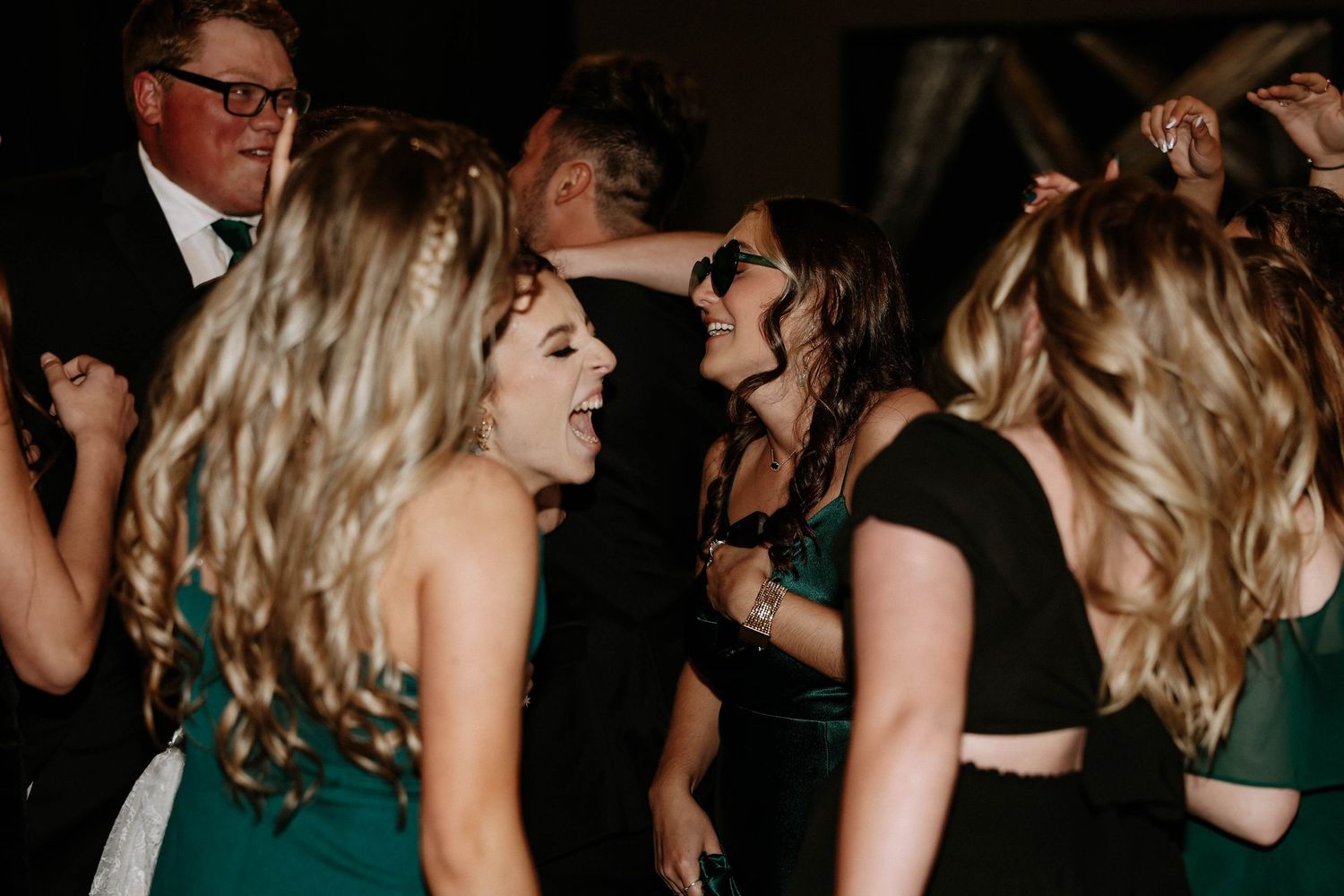 Guests dancing and celebrating at a wedding reception in elegant green and black formal attire.