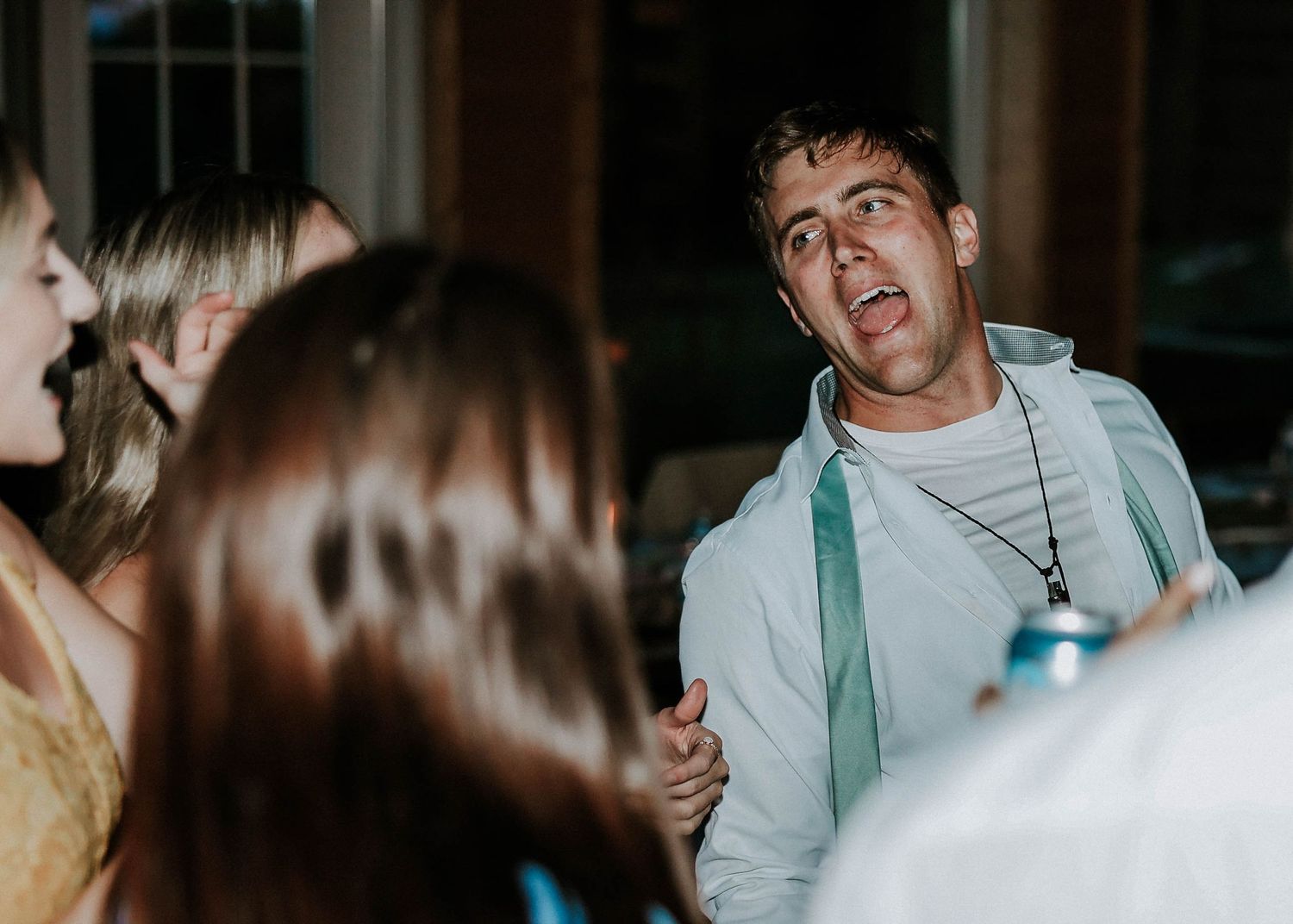 Man in white hoodie with surprised expression dancing at an outdoor evening party event.
