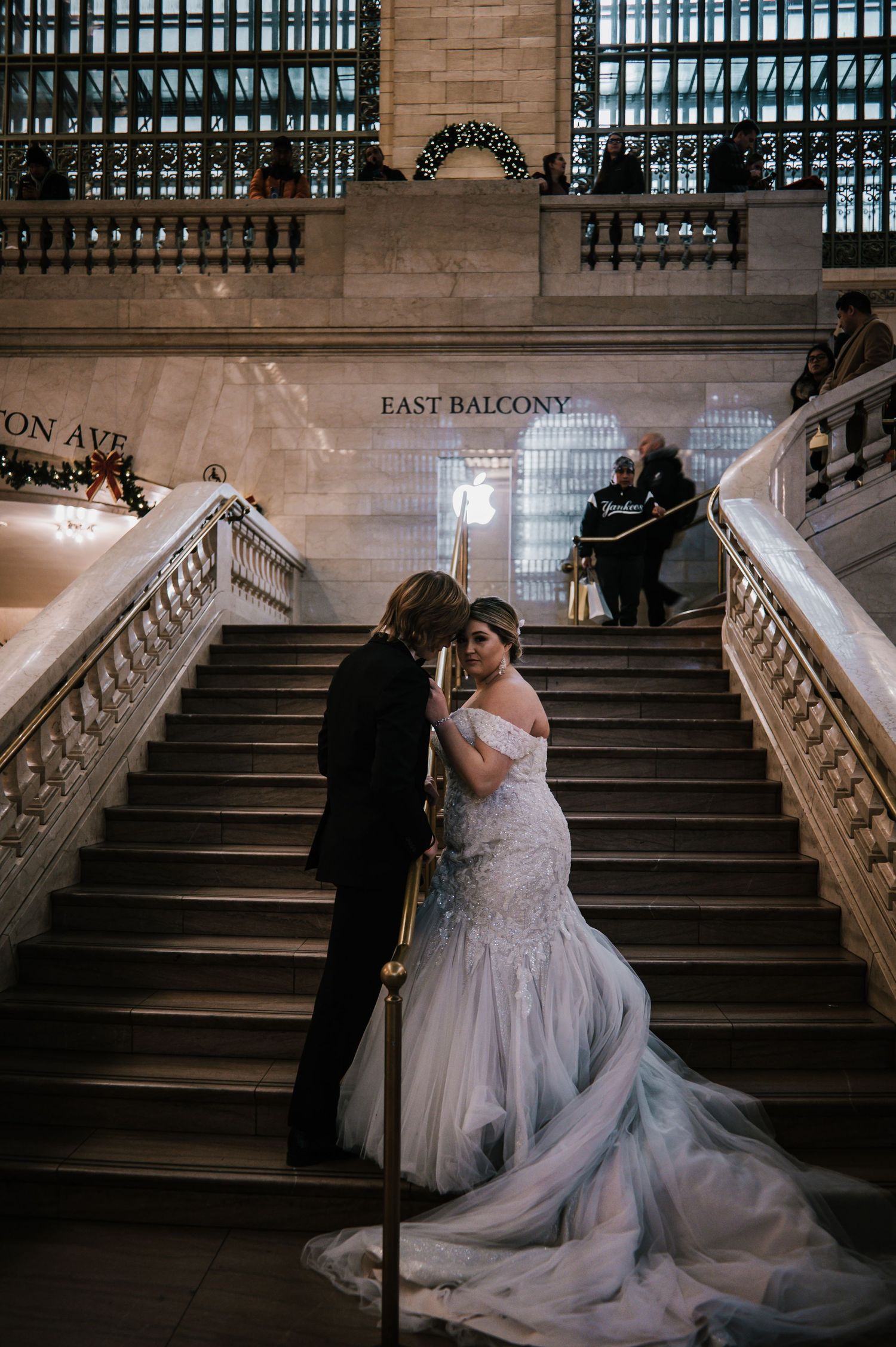 Bride and groom sharing a romantic moment on Grand Central Terminal East Balcony stairs in NYC.