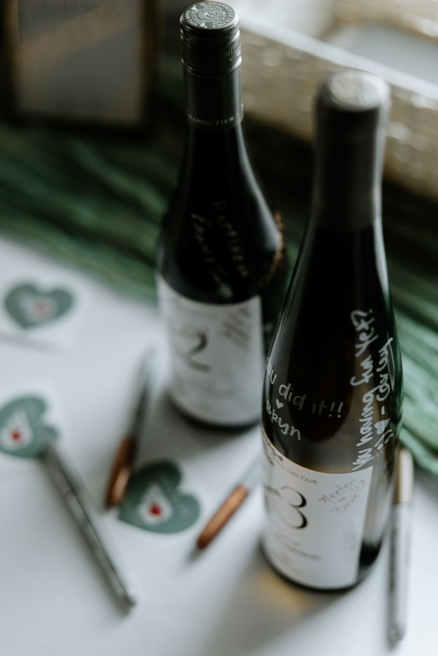 Guests sign wine bottles with handwritten messages as a unique wedding guestbook alternative.