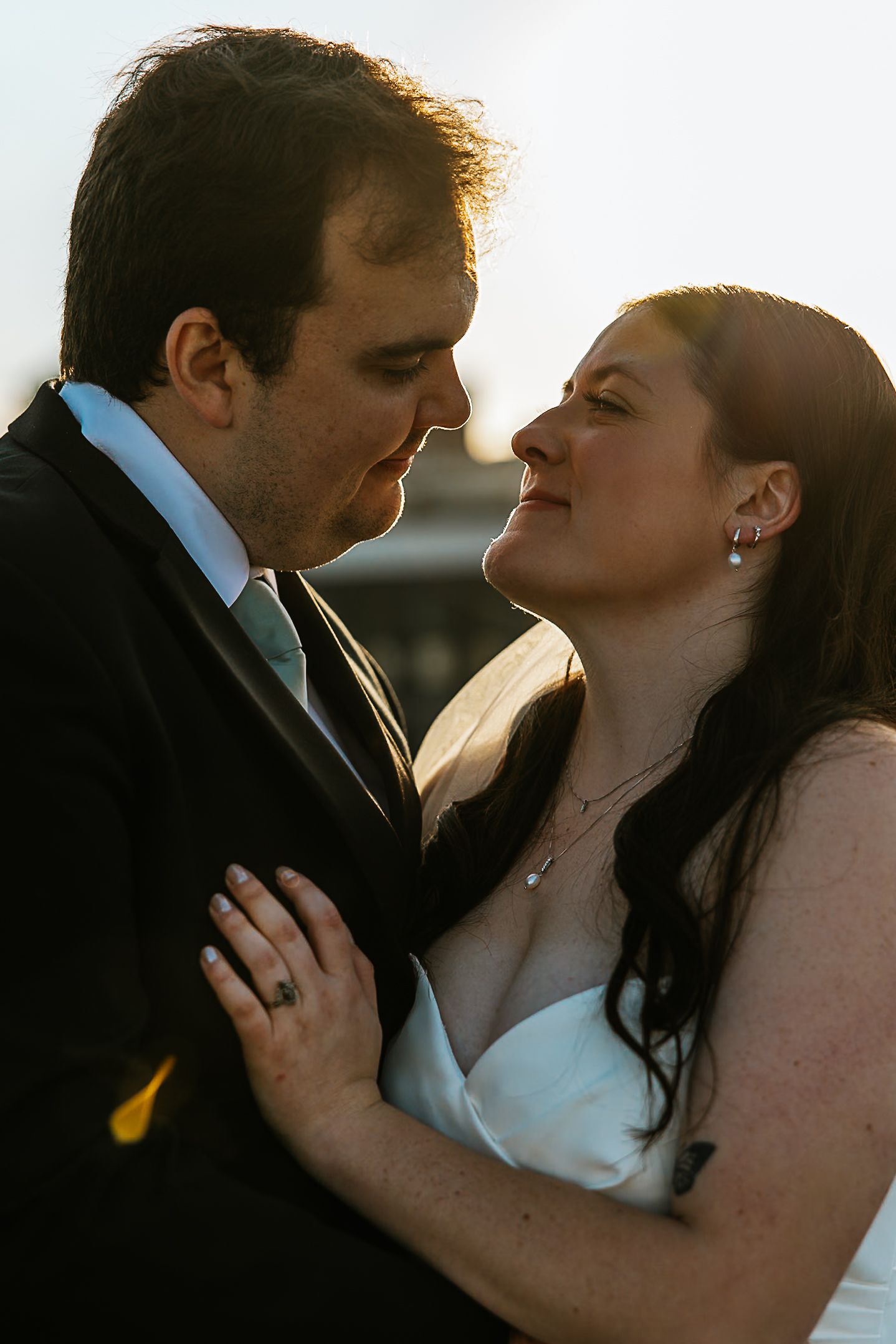 Bride and groom gazing into each others eyes in warm golden sunset light.