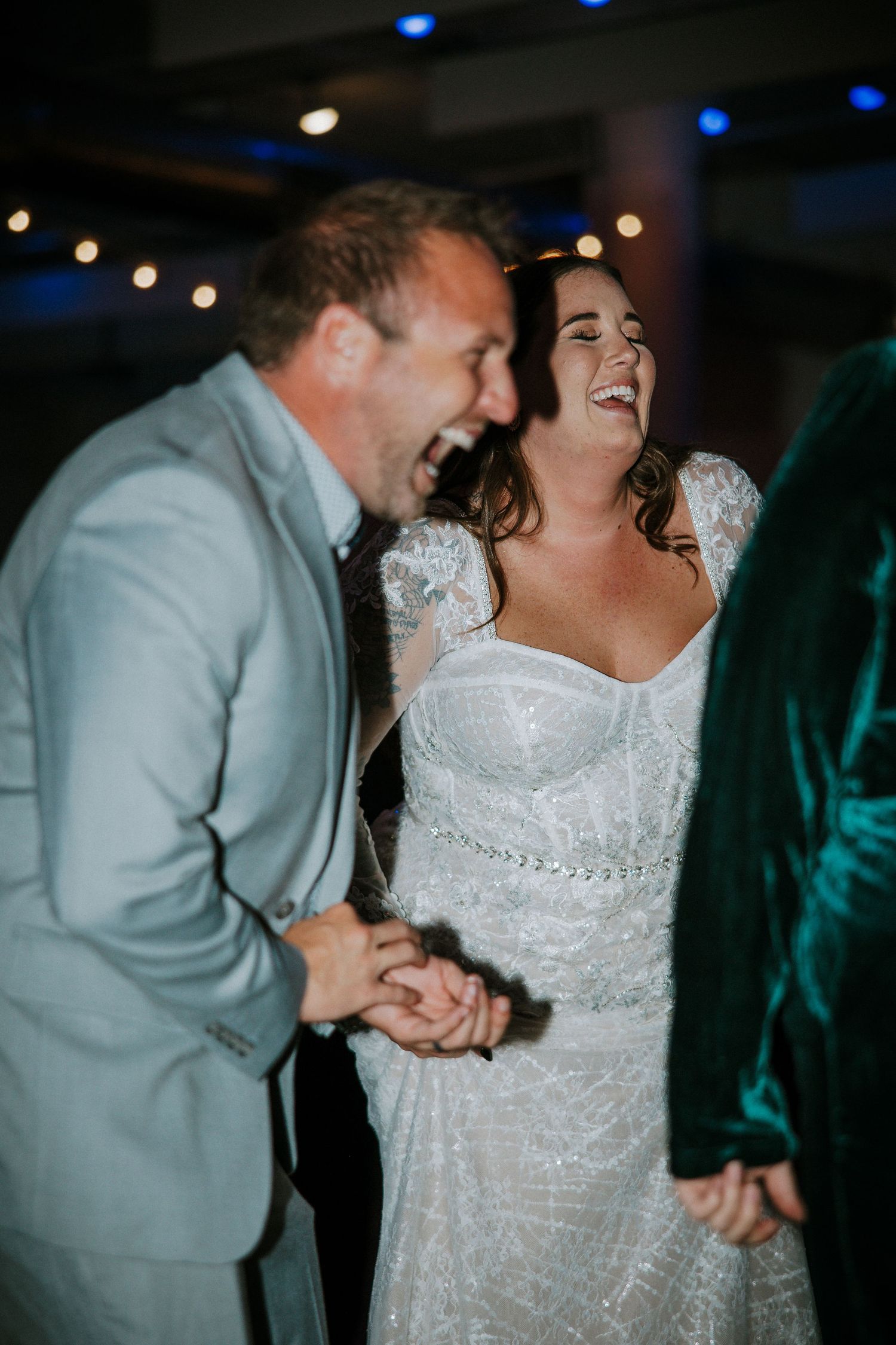 A laughing bride in a beaded gown dances joyfully with a guest at her wedding reception at The Red Space in Cleveland, Ohio