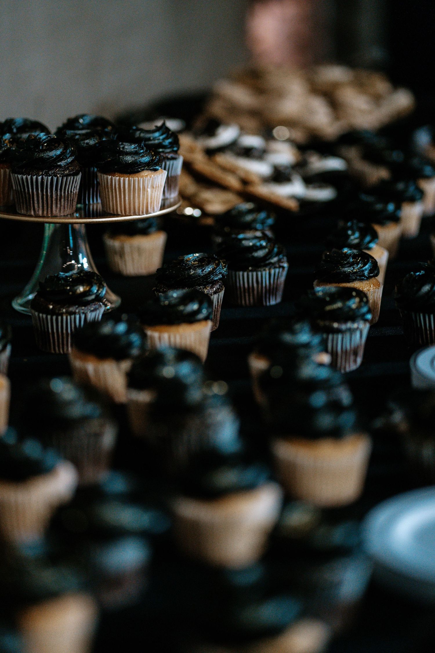 Dark chocolate frosted cupcakes displayed on a dessert table at an elegant event.