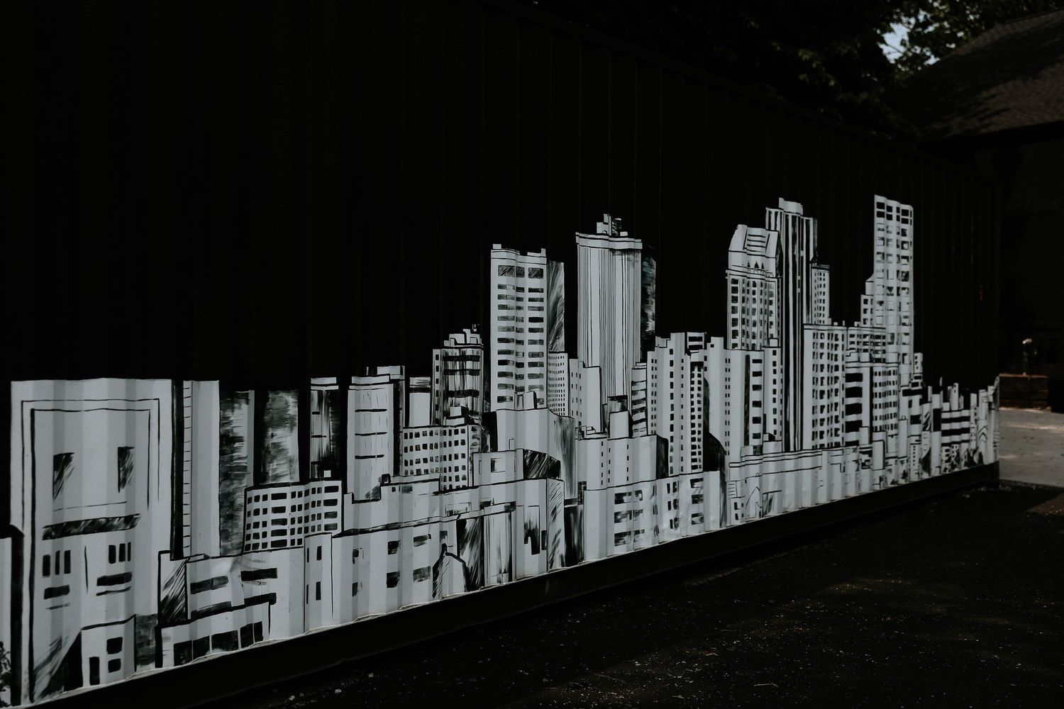 Black and white mural of a city skyline with tall buildings on a dark wall.