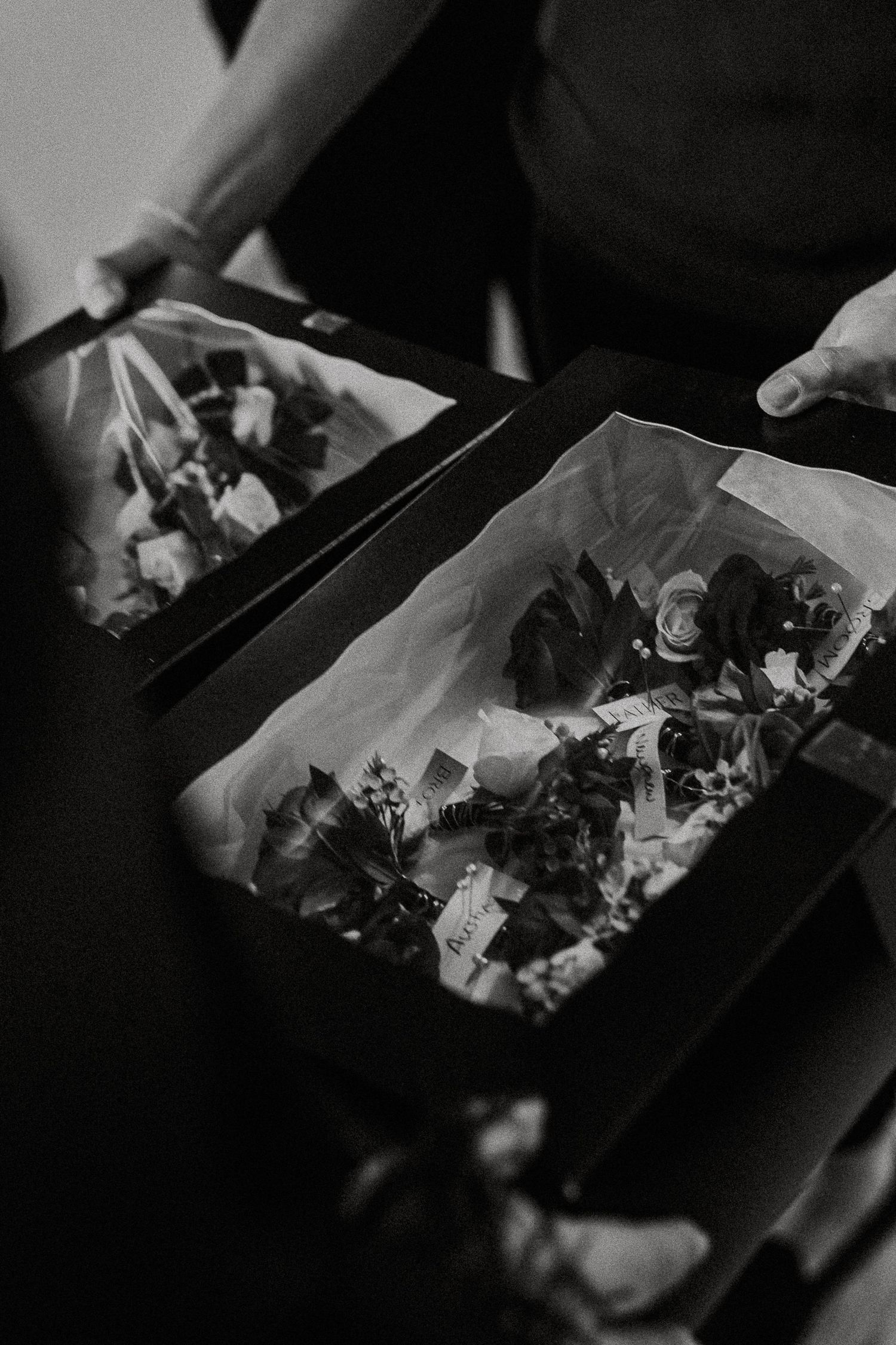 Black and white close-up of floral arrangements in boxes for a wedding.