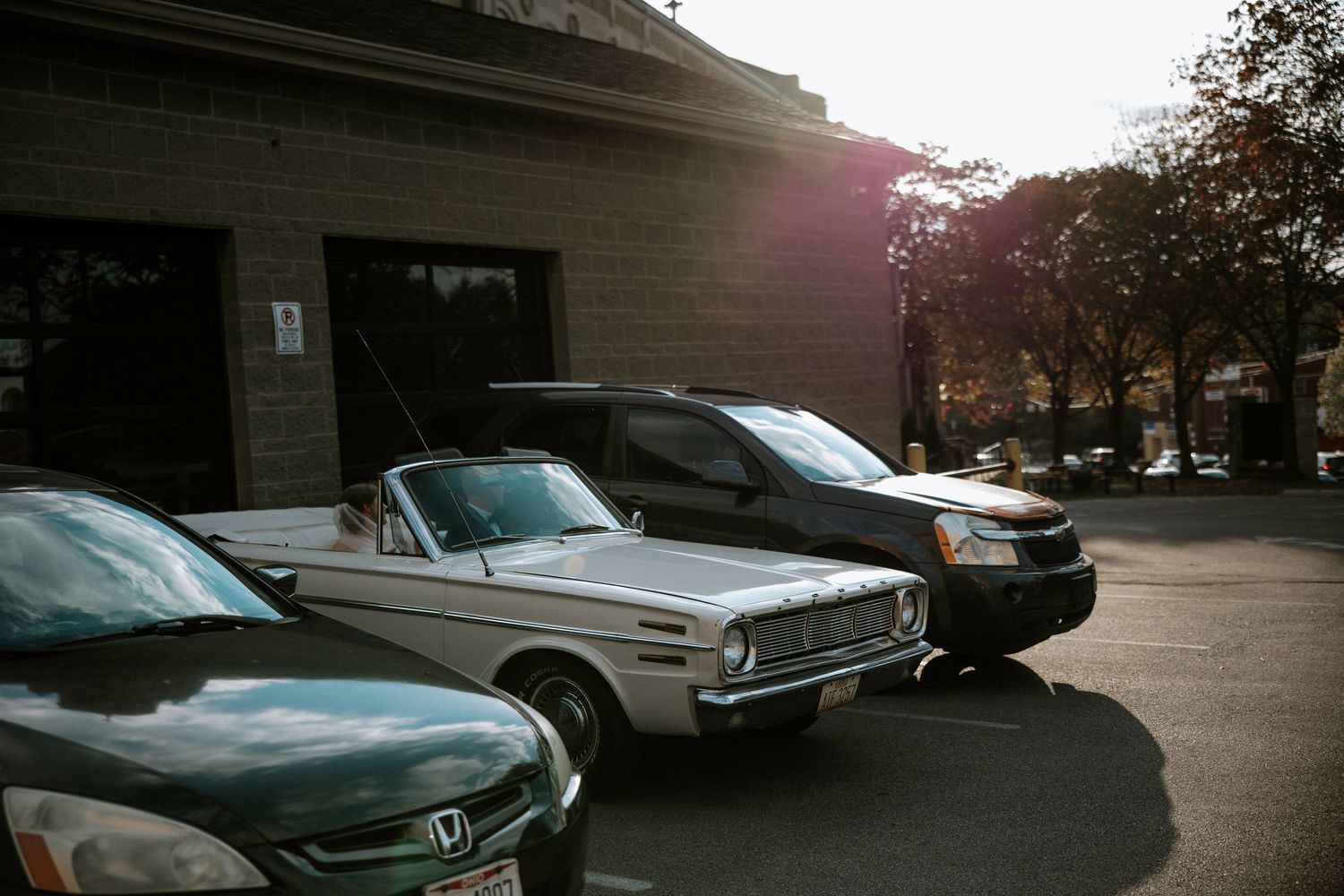 Vintage white convertible classic car parked in a sunlit lot beside a Honda on a wedding day at Urban Artifact in Cincinnati, Ohio