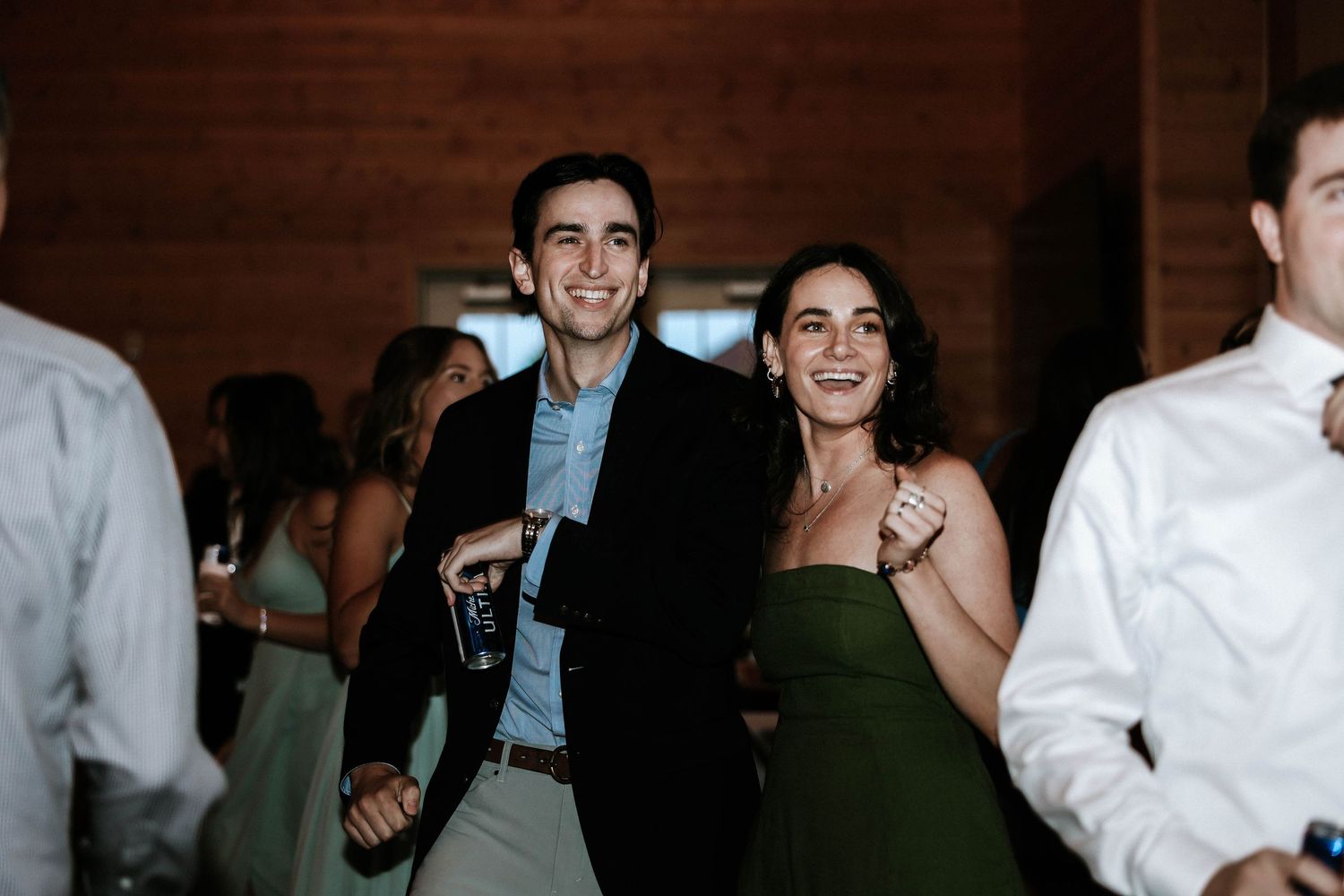 Smiling couple in formal attire enjoying a wedding reception on the dance floor.