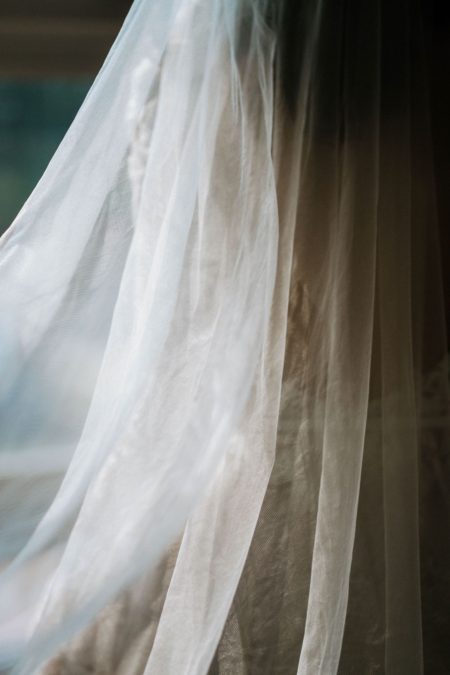 Soft white sheer curtain fabric billowing gently in natural light near a window.