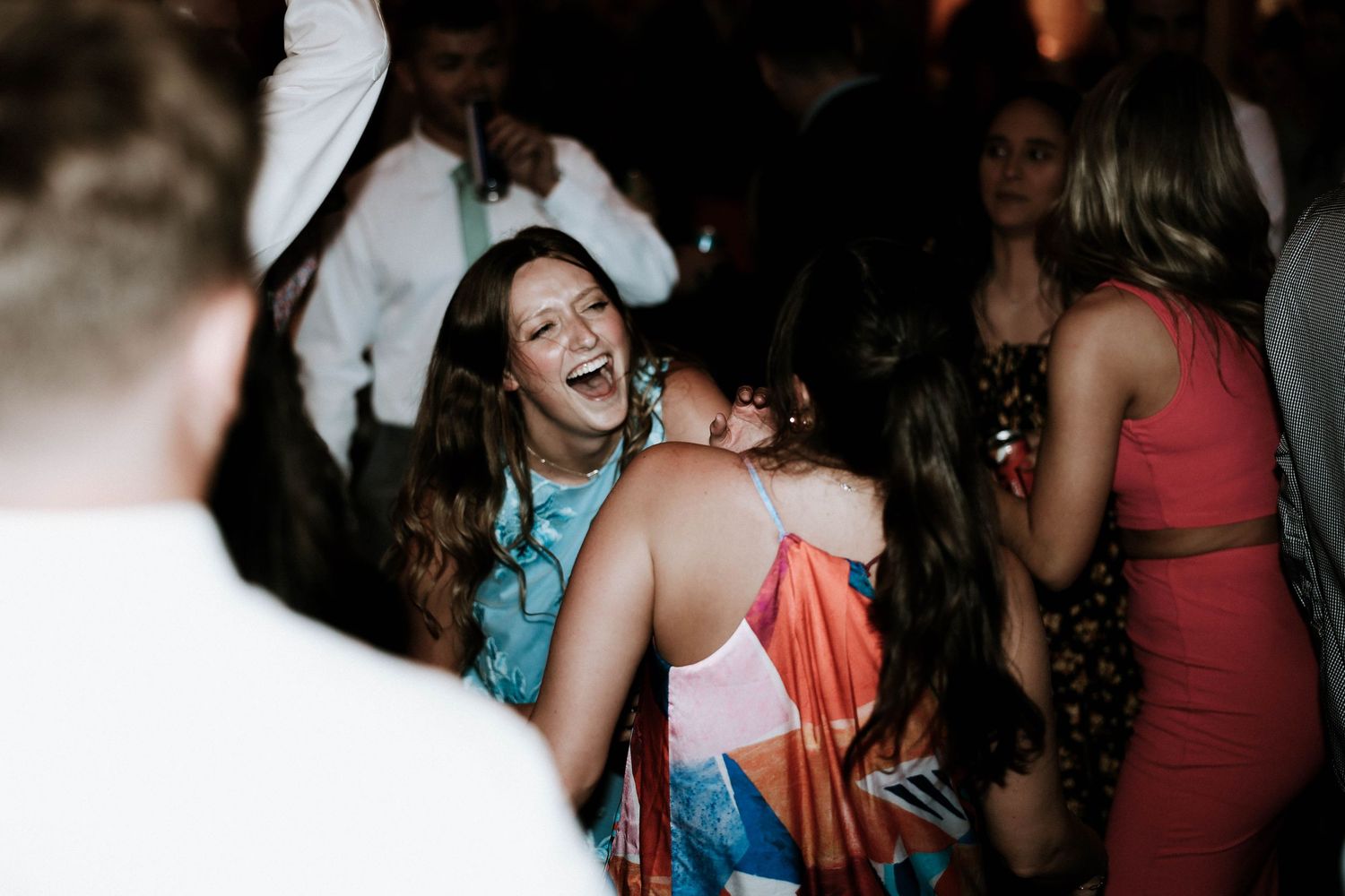 Guests laughing and dancing joyfully at a lively wedding reception party.