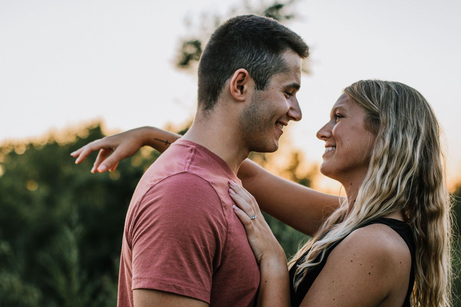 A smiling couple gazes at each other outdoors at sunset at Oakes Quarry Park in Dayton, Ohio