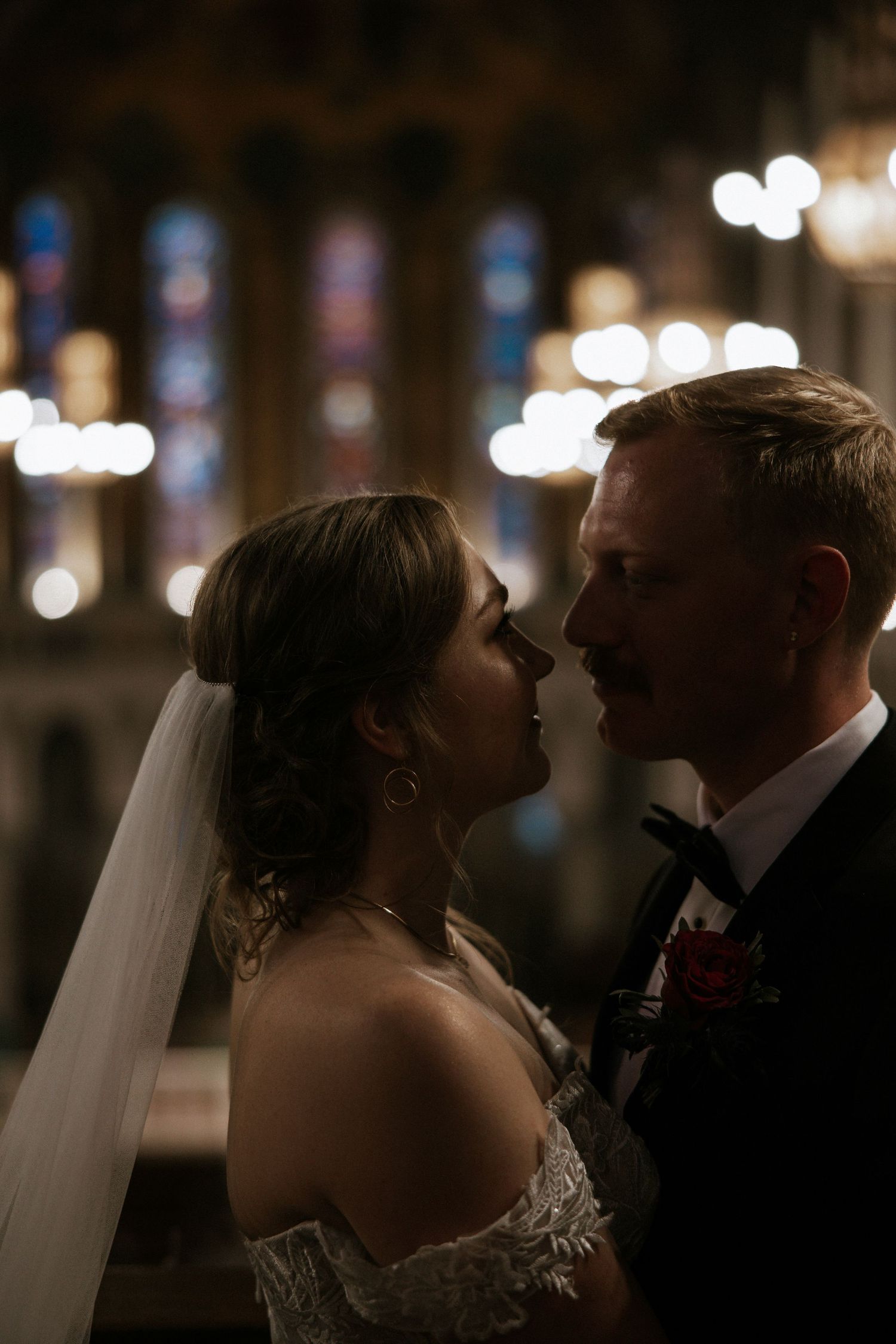Romantic silhouette of bride and groom nearly kissing with glowing stained glass windows in background in Cincinnati, Ohio