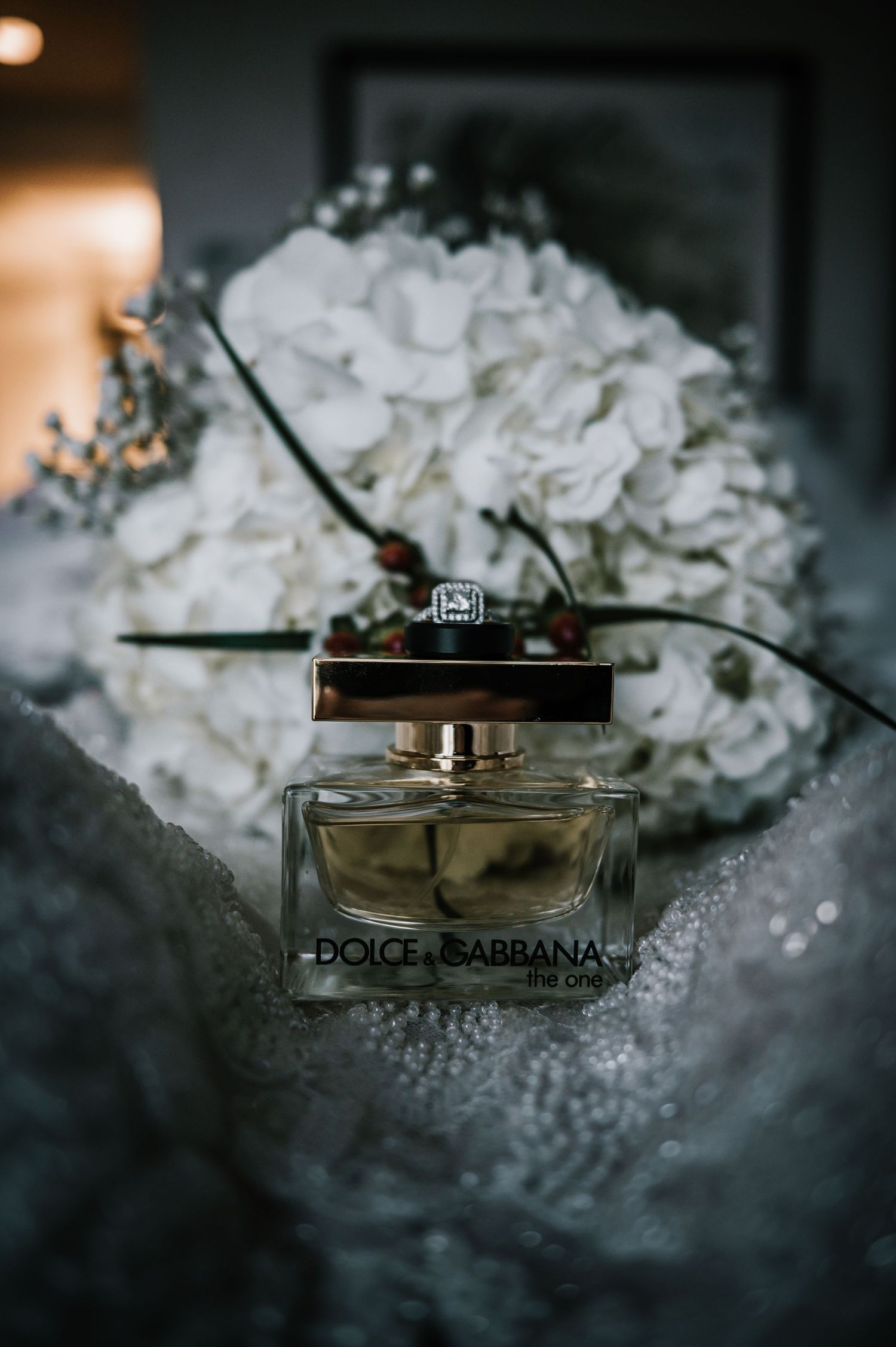 Dolce & Gabbana The One perfume with white hydrangea bouquet on bridal gown.