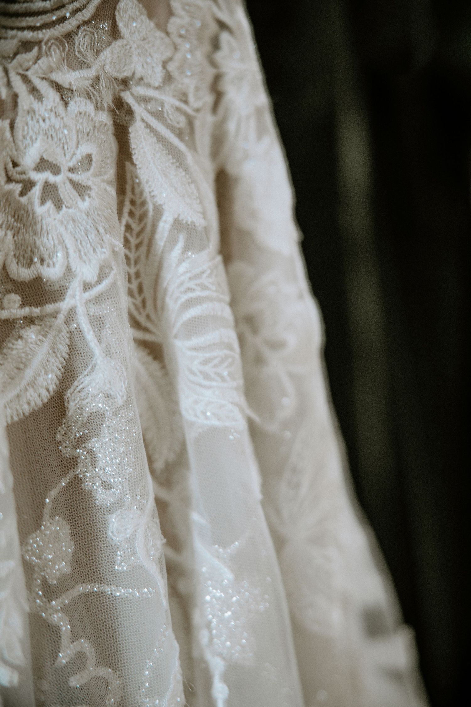 Close-up detail of intricate floral lace and beading on a luxurious off-shoulder wedding dress at Urban Artifact in Cincinnati, Ohio