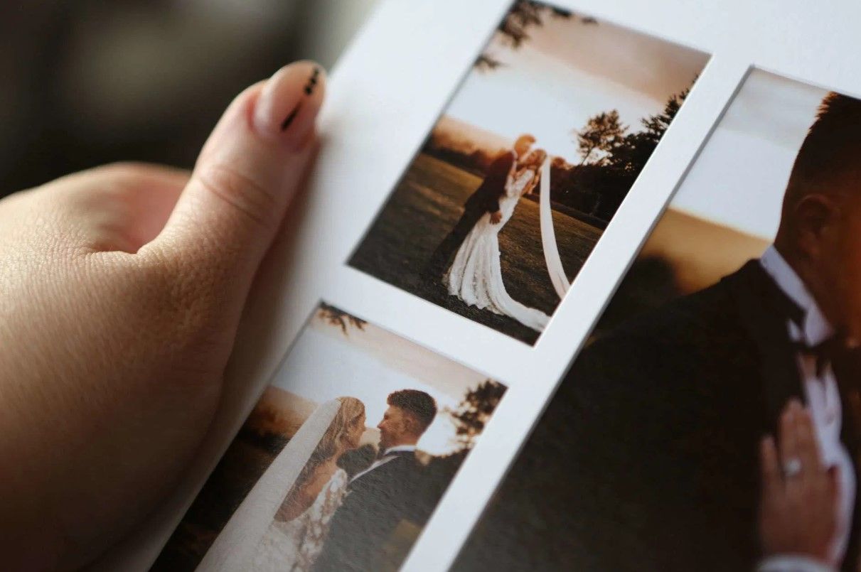 Close-up of hands holding a wedding photo album featuring romantic sunset couple portraits in Cincinnati, Ohio