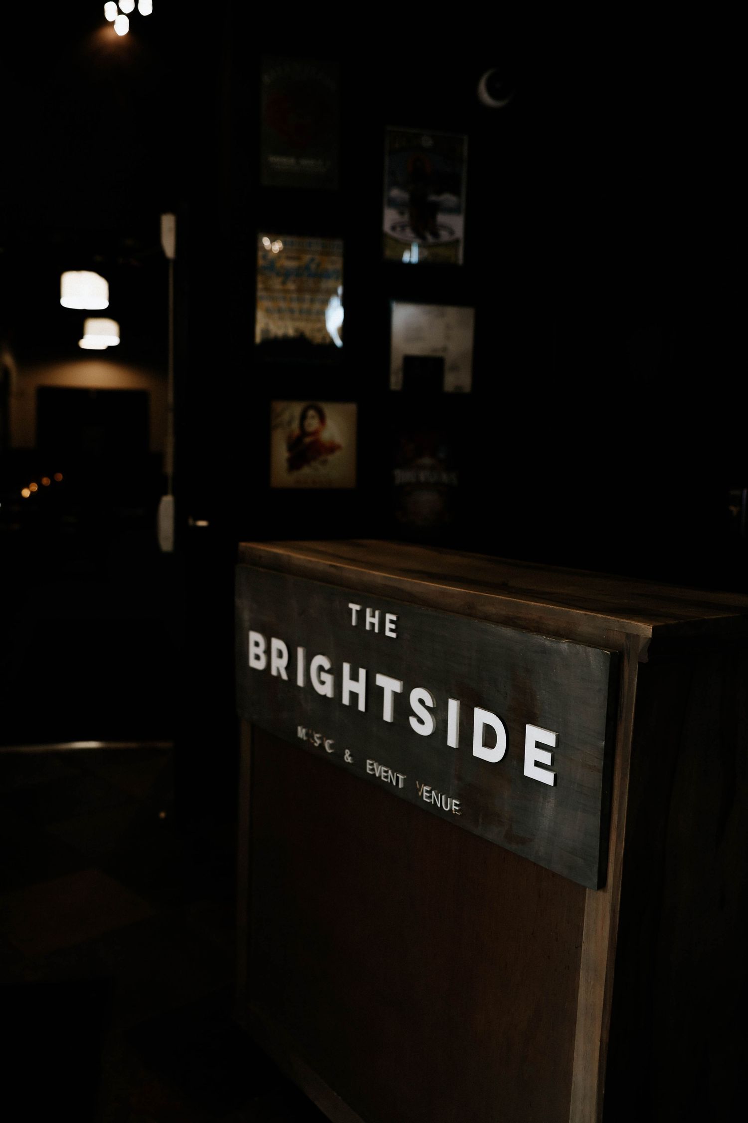 Dark interior sign reading The Brightside Music and Event Venue, with dimly lit photo displays visible in the background.