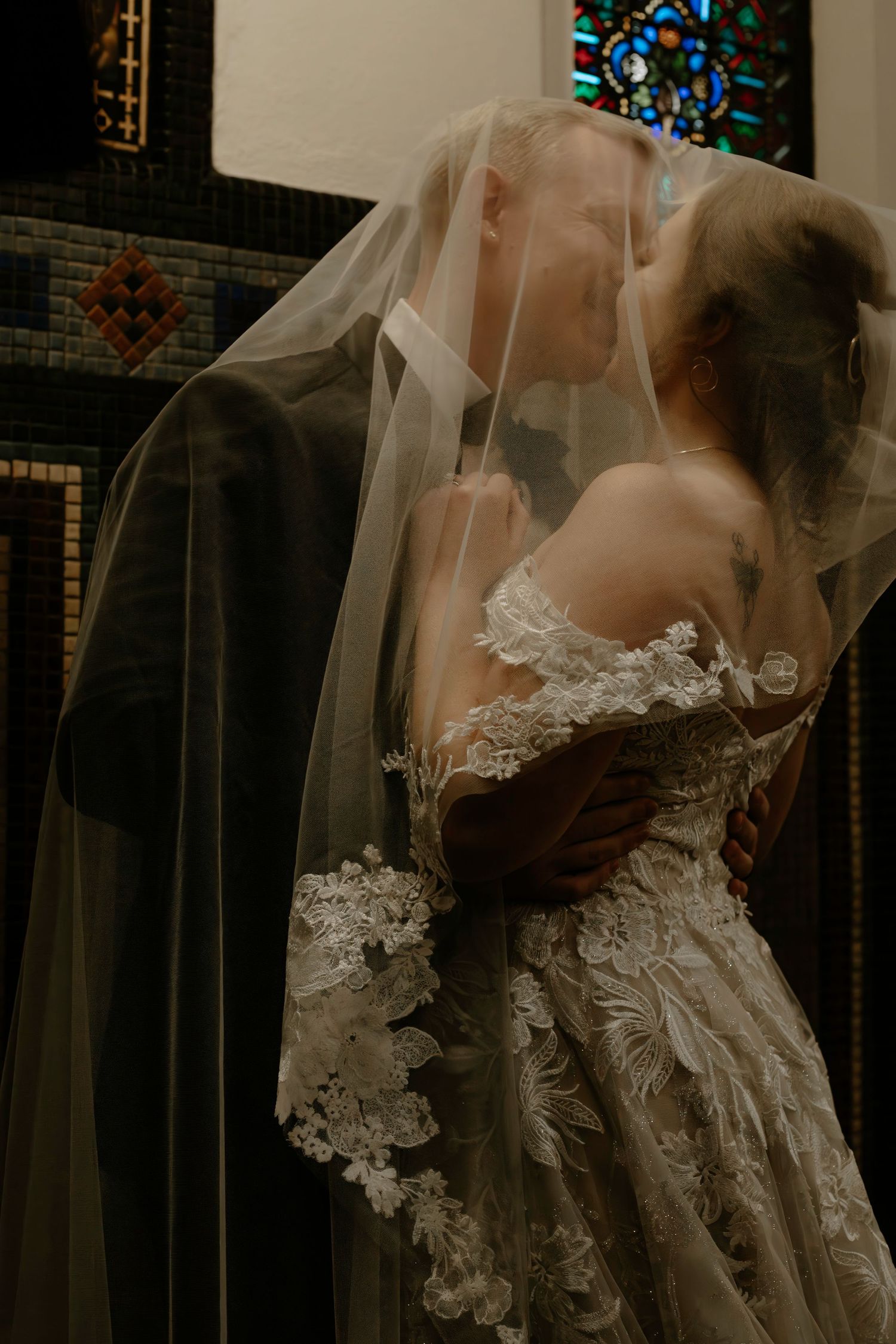 Romantic portrait of bride and groom kissing beneath flowing lace wedding veil in church setting in Cincinnati, Ohio