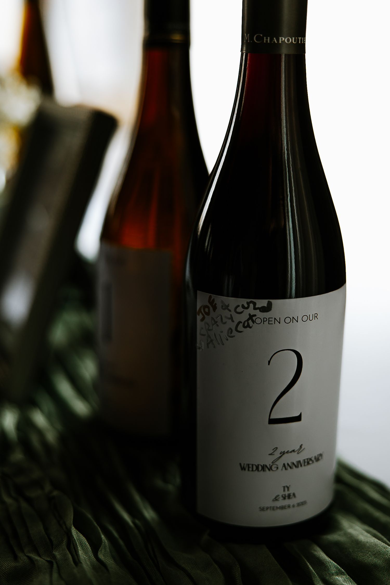 Wine bottle labeled open on 2nd wedding anniversary displayed as a wedding keepsake.